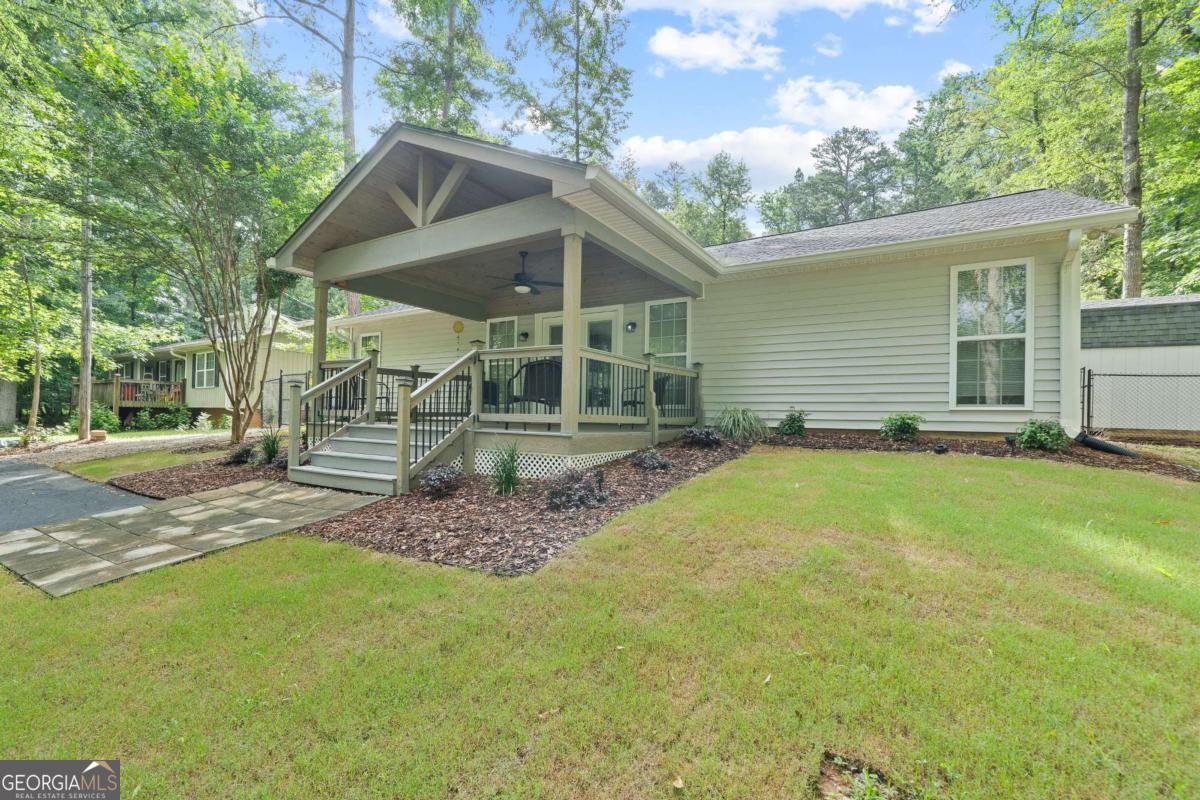 This beautifully updated 3-bedroom, 2-bath ranch home sits on a spacious 0.6-acre lot directly across from Lake Sinclair. A newly built, covered front deck offers the perfect spot to relax and take in stunning seasonal lake views. Inside, luxury vinyl plank flooring, fresh paint, and updated light fixtures create a bright and inviting atmosphere throughout the home. The open floor plan features a vaulted ceiling in the main living area, enhancing the sense of space. The kitchen is equipped with solid surface countertops, a breakfast bar, and brand-new stainless-steel appliances. The owner's suite is designed for comfort with a tray ceiling, walk in closet with built-ins, double vanity, jacuzzi tub, and a separate shower. Two additional bedrooms share a full bath. Step outside to the beautiful, newly landscaped, fully fenced backyard featuring a cozy firepit-perfect for crisp evenings under the stars- privacy, and a large outbuilding for extra storage space. Completing the package is a new HVAC system installed in March 2025 and new roof installed in 2023. One year home warranty to buyer at close! Located just minutes from public lake access, this home offers the perfect blend of charm, updates, and convenience. Don't miss this incredible opportunity!