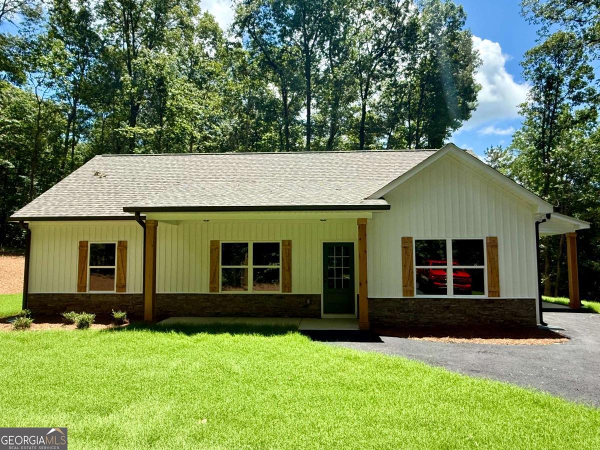 NEW CONSTRUCTION RANCH ON 3 QUIET ACRES - NO SUBDIVISION OR HOA!!! Act now for a FREE appraisal and $3,000 in incentives with our preferred lender. Conditions apply. See listing agent for details. This stepless ranch home is under construction on a serene 3.098-acre lot -- offering the perfect blend of privacy and convenience. Conveniently located north of Buchanan off of Hwy 27 going towards Cedartown. Featuring 3 bedrooms and 2 full bathrooms, the home showcases an open layout with vaulted ceilings in the main living and dining areas for a spacious, airy feel. There's still time for buyers to add their own personal touches! Contact the listing agent today! The kitchen is designed with granite countertops, a counter-height bar, and a stainless steel appliance package including an electric range, built-in microwave, and dishwasher. The split-bedroom layout provides privacy, and the primary suite features a walk-in closet and a bathroom with double vanities, framed mirrors, granite countertops, and a stand-up shower. The two secondary bedrooms are generously sized and share a full bathroom with a granite vanity and a tub/shower combo. Ceiling fans are included in the living room and primary bedroom. Outside, the home will be finished in low-maintenance vinyl siding with a stone water table for added curb appeal. This floor plan includes an attached carport. Tract 2 is also available and being marketed without the carport in another listing. Don't miss this opportunity to customize your dream home in a peaceful country setting! ***Photos are of a home similar to the one being constructed, not of the actual subject property.***Please note that the property is in the VERY EARLY stages of construction/clearing.***
