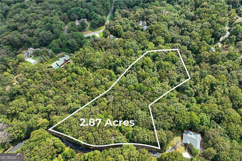 2.87 ACRES OF PRIVATE, WOODED LAND! This beautiful property offers the perfect blend of seclusion and convenience. Tucked away in a serene, wooded setting, it provides the ultimate escape while remaining just minutes from all the amenities you need. Enjoy easy access to GA-400, making your commute a breeze. You'll be close to a variety of shopping and dining , as well as the local hospital. The land features a small, tranquil stream and paved road frontage, adding to its appeal and accessibility. This is a rare opportunity to build your dream home in a private, natural environment without sacrificing a convenient location. Don't miss out on this exceptional piece of property!