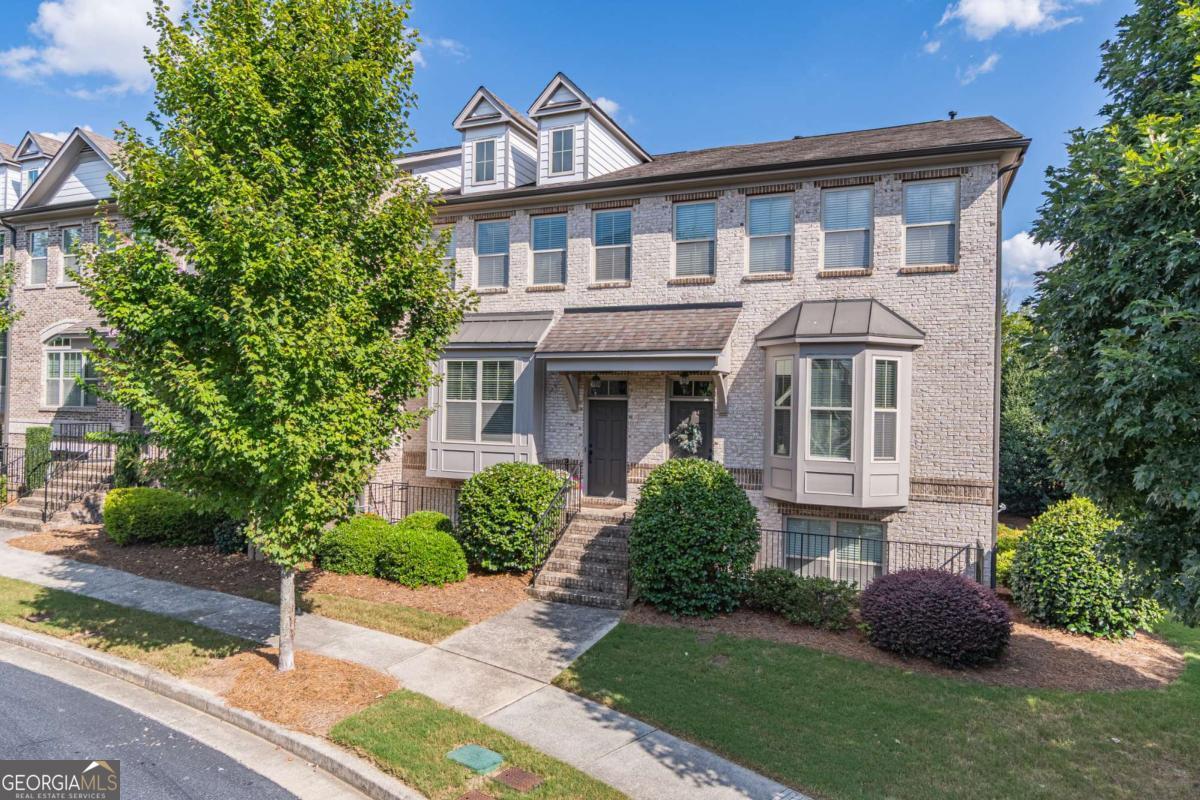 Welcome to this beautifully maintained 3-bedroom, 3.5-bath townhome in the highly desirable gated community of Three Bridges in Suwanee. Designed for modern living, this home features an open floor plan with abundant natural light and hardwood floors throughout the main level. The chef's kitchen impresses with stainless steel appliances, granite countertops, a breakfast bar, and a clear view to the dining area and fireside family room. A dedicated office space offers the perfect work-from-home setup. The lower level provides a private bedroom with a full bath-ideal for guests or in-laws. Upstairs, the luxurious owner's suite showcases a tray ceiling, walk-in closet, and a spa-like en suite with double vanities, a tiled shower, and a soaking tub. Additional highlights include a 2-car garage, a private deck, and appliances that are all 2 years old or newer. Set within the beautifully landscaped Three Bridges community, residents enjoy tree-lined streets, courtyards, and resort-style amenities including pickleball and tennis courts, swimming pool, clubhouse, and playground. The HOA conveniently covers exterior painting, roofs, lawn care, and termite protection. Perfectly located near top-rated schools, Suwanee Town Center, parks, and the Greenway, this townhome offers the ideal blend of style, comfort, and convenience.