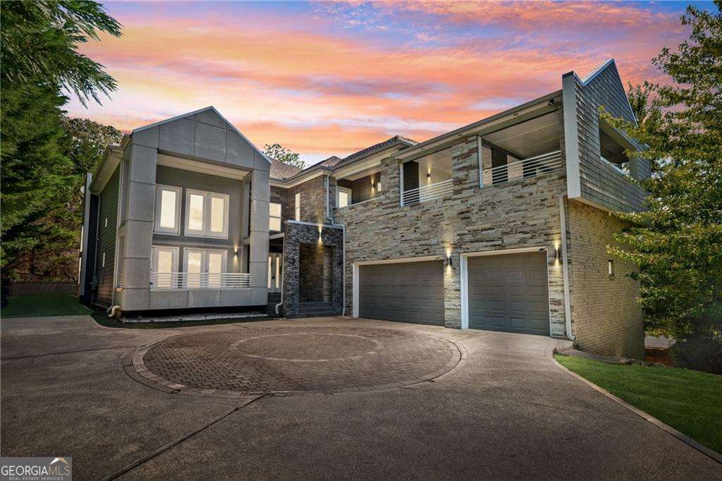 Welcome to this striking contemporary residence, where thoughtful design meets gracious living in a blend that feels both luxurious and warm. As you step into the dramatic two-story great room, walls of windows draw in natural light, while crisp architectural lines and soaring ceilings create a gallery-like strength tempered by comfort. A flexible layout features two kitchens and a welcoming guest bedroom on the main level, making entertaining and daily living both comfortable and convenient. With ample garage space for three vehicles, this home is as practical as it is beautiful. Step outside from the dining room onto the covered back patio, leading to the beautifully landscaped backyard and a charming gazebo-ideal for quiet afternoons or starlit gatherings. Downstairs, the fully finished basement includes an in-law suite with its own full kitchen, an exclusive exterior entry, and an interior entry-perfect for extended family, guests, or a private workspace. The basement also boasts a media room equipped with WiFi projector and a huge 16' wide projection screen, creating a premium home theater experience. Upstairs, the expansive master suite is a phenomenal retreat: custom shelving, an impressive custom-built walk-in closet, and a spa-level bath that showcases a frameless glass shower and a soaking tub. You'll love stepping out onto the massive covered deck off the master suite, where morning light and evening breezes mingle above your private, lushly landscaped yard. Every room is designed with lifestyle in mind, from quiet nooks with light streaming in to open entertaining zones that flow naturally. The home was crafted to deliver both grandeur and coziness. Just outside your door, you'll discover a host of nearby recreation and local treasures. The nearby Sewell Mill Creek Loop in East Cobb Park provides an easy walking trail under tree canopies, perfect for daily strolls or birding. The historic Strand Theatre in Marietta offers live performances, classic films, and cultural events in a beautifully restored atmosphere. This home offers an exceptional balance: bold, contemporary architecture with inviting spaces; indoor sophistication with seamless outdoor living; and a prime location that places you minutes from nature, culture, and the charm of Marietta.