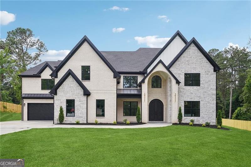 Welcome to The Manor at Smithtown, an intimate sanctuary of just six privately gated estates where architectural grandeur and modern sophistication converge in one of Suwanee's most prestigious addresses in award-winning North Gwinnett District. Each residence is gracefully positioned on a graded homesite of an acre or more, designed to provide a rare balance of privacy, elegance, and distinction. Lot 2 - The Zarah Plan is a triumph of artistry and scale, offering more than 6,300 square feet above grade of bespoke living space, complemented by a stately three-car garage and a private, gated homesite of over one acre. The exterior facade, constructed of four-sided brick with hand-selected stone accents and adorned with custom luxury garage doors, establishes a commanding presence from the moment of arrival. Beyond its threshold, a soaring two-story foyer, anchored by a breathtaking floating staircase, reveals interiors of refined grandeur, where artisan millwork, curated wall treatments, and sweeping sightlines create an atmosphere of timeless sophistication. The heart of the home is an extraordinary chef's kitchen, designed with bespoke cabinetry, quartz countertops, and professional-grade appliances, all centered around a dramatic oversized island sculpted for both function and beauty. A second full prep kitchen, complete with additional cooktop, vented hood, and custom pantry cabinetry, provides an elevated level of utility and refinement, perfectly suited for grand entertaining and everyday culinary pursuits alike. The dramatic two-story living room, crowned and illuminated by designer light fixtures, is defined by walls of expansive glass that dissolve into the outdoors, unveiling a covered terrace with a fully appointed outdoor kitchen. Here, the residence seamlessly transitions into its surroundings, overlooking lush grounds ideally designed to accommodate a future resort-caliber pool, creating an unparalleled setting for both intimate gatherings and lavish soirees. The main-level owner's retreat serves as a private sanctuary, framed by picture windows that capture serene views of the backyard. Its spa-inspired bath is wrapped in full-height designer tile and features a frameless glass shower, freestanding soaking tub, dual vanities, and a boutique-style walk-in closet. The upper level continues the theme of indulgence, with oversized secondary bedroom suites, each with its own private bath and walk-in closet. A dramatic loft, private office, wet bar, and secondary laundry suite elevate convenience while reinforcing the home's bespoke luxury. Every detail of the Zarah Plan reflects a devotion to craftsmanship and architectural mastery, from the soaring 10-foot ceilings on the main level to the extensive millwork and custom cabinetry woven throughout the residence. With completion anticipated in Spring 2026, this home offers the rare opportunity to personalize a timeless estate in one of Suwanee's most exclusive enclaves. Photography reflects a previous build. Active Construction Site. All finishes, specifications, and floorplan have multiple variations and are subject to change.