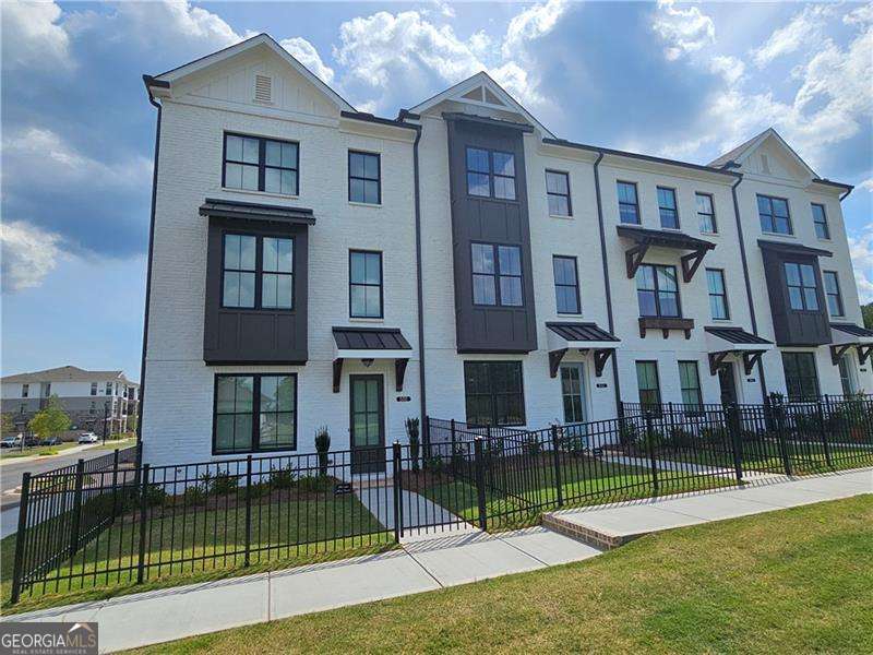 Enjoy living in this state of the art brand new corner lot just around 2000 sqft townhome (Glendale floorplan) built by Providence group which is located in Cumming's newest master-planned community, Sawnee Village. This smart home features 3 generous size bedrooms, 3.5 tiled bathrooms, lots of windows to allow for ample natural light, beautiful mountain view from the front of home, a fenced in private front yard, rear entry 2 car garage, level 2 car driveway, lots of windows to allow for ample natural light, beautiful mountain view from the front of home, a fenced in private front yard, 2 car garage, a level 2 car driveway, tall windows and doors, crown moldings throughout, nice light fixtures, EV charging available in the garage, a tankless water heater, climate controlled attic and a large deck perfect for entertainment. First floor features a nice size bedroom with French doors and a private full bathroom with upgraded walk-in shower, perfect for guests or a home office or an in-law suite. The main level features 9' ceilings, oversized dual-pane windows, and a sunlit open-concept layout. The kitchen features a 9' quartz island, white linen 42" soft-close cabinetry, Xenon under-cabinet lighting, and a 4x12 subway tile backsplash, ENERGY STAR Certified GE stainless steel appliances, including a side-in gas range, microwave, vent hood vented to exterior, dishwasher, and a refrigerator. The main level features 9' ceilings, oversized dual-pane windows, and an open-concept layout with lots of natural light. The kitchen boasts a 9' quartz island, white linen 42" soft-close cabinetry, Xenon under-cabinet lighting, and a 4x12 subway tile backsplash. Enjoy ENERGY STAR Certified GE stainless steel appliances, including a side-in gas range, microwave, vent hood vented to exterior, dishwasher, washer dryer and a refrigerator. The oversized private rear deck is equipped with GFCI outlets, perfect for grilling or lounging. The level also includes elegant 5" crown and base molding throughout. The top level features a spacious owner's suite featuring a walk-in closet, soaking bath tub, separate walk-in shower, and dual quartz vanity with linen cabinetry. The top level has a laundry room with a washer & dryer, linen closet and two spacious bedrooms including master and very nicely finished bathrooms. A secondary guest bedroom with its own private bath is located at the front of the home. Laundry is conveniently positioned just outside the owner's suite. Additional smart features include a Nest Video Doorbell, Nest Hub 7" Display, and WiFi Mesh Point. Sawnee Village offers exceptional access to GA-400, top Forsyth County schools, and future on-site retail/dining. The neighborhood also features a lot of guests parking spots and is located mins from to GA-400, top Forsyth County schools, and future on-site retail/dining. This is the only new townhome community walkable to retail, dining, and entertainment and shopping coming soon to Market Square within the complex. Please go to Providence group builder website to see a video tour of this beautiful and decorated model to visualize the home in decorated state.