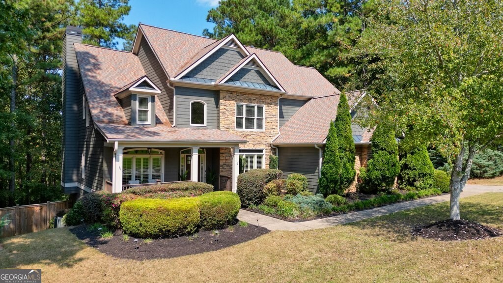 Distinguished Craftsman-style home constructed with hardiplank and stone exudes timeless charm, character, and impressive curb appeal. Classic details include large windows throughout, a hallmark of Craftsman architecture that fills the home with natural light. An inviting front porch with durable Trex-type flooring provides the perfect space for relaxing and entertaining family and friends. Inside, the open floor plan features soaring ceilings in the entry and family room, creating an airy and welcoming atmosphere. A formal dining room and a versatile study or living room flank the entryway, both boasting large windows and elegant plantation shutters. Gleaming hardwood floors flow throughout the main level and up the striking staircase. The spacious family room is lined with multiple windows that showcase long-range views of the scenic Etowah forest. The floor plan seamlessly transitions into the casual dining area, and keeping room with a cozy fireplace and gourmet with 5 burner gas cooktop, double ovens, granite counters and walk-in pantry. Step outside to the screened porch, a favorite spot to unwind and take in the picturesque surroundings, complete with a newly painted floor. Upstairs, you'll find four bedrooms, including a luxurious primary suite with a frameless glass shower, a roomy jetted tub, double-sink vanity, and a walk-in closet. A large bedroom at the end of the hall shares a bath with a front-facing bedroom, while a fourth bedroom enjoys the privacy of an en-suite bath. The convenient second-floor laundry room offers cabinetry, a storage closet, and a utility sink. Other notable features: 6 yr old roof, 2 new HVAC units less than 3 years old, Nest thermostats, Ring doorbell, and wired for alarm system and outdoor lights on timers. The spacious unfinished basement is stubbed for a bath and ready to be customized to suit your needs. The fully fenced backyard features a gate opening directly to the Etowah forest and eventually the Etowah River. A three-car garage with an epoxy floor provides ample space, including a ceiling-mounted kayak rack for added convenience. This exceptional home blends classic Craftsman elements with modern amenities, offering comfort, style, and access to nature.