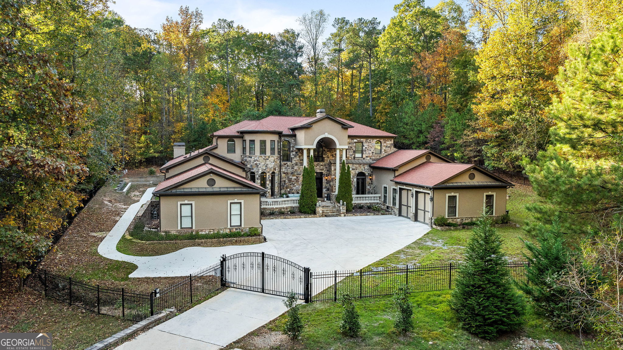 Nestled on a sprawling one-acre gated lot at the footsteps of Kennesaw Mountain, this luxurious estate captivates from the very first glance. The front elevation impresses with its stately columns, setting a grand tone as you approach. Step through the front doors into a dramatic two-story entrance, where a swirling staircase sweeps upward, creating an atmosphere of elegance and sophistication. The main level reveals an expansive living room, bathed in natural light from a wall of windows. This inviting space features gleaming hardwood floors, a cozy fireplace, and an adjacent bar area, perfect for entertaining or unwinding. Nearby, a dedicated office offers an ideal workspace, adorned with a stunning chandelier and direct access to the front porch, combining functionality with a touch of refinement. Retreat to the primary bedroom on the main floor's sanctuary of comfort with its spa-like bathroom, complete with a separate soaking tub, a spacious shower, and a custom walk-in closet designed to accommodate an extensive wardrobe. Additionally, the main level includes a guest bedroom, ensuring convenience and privacy for visitors. At the heart of the home, the chef's kitchen is a culinary masterpiece. Outfitted with high-end appliances from brands like Miele and Wolf, the kitchen offers ample cabinetry for storage, an extended pantry with custom shelving, and a large island that serves as both a workspace and a gathering spot. Adjacent to the kitchen, the keeping room presents a casual living space with a rustic stone fireplace and a wraparound view of the backyard, creating a seamless indoor-outdoor connection. The upper level is thoughtfully designed with three additional bedrooms, each with its own bathroom, providing comfort and privacy. A spacious bonus room adds versatility to this level, ready to adapt to various needs, from a playroom to a media room. The fully finished basement is a world of its own, perfect as an in-law suite with its private entrance. It features a large living area, a well-appointed kitchenette with a quartz-topped island, a gym area, a serene spa room, and two additional bedrooms. This space is crafted for independent living, offering both style and practicality. Step outside into a backyard oasis that defines relaxation and luxury. The saltwater, heated pool is a true highlight, equipped with night lighting to enhance evening ambiance. Beautiful landscaping surrounds the pool area, creating a private retreat that feels like a personal resort. For the car enthusiast, this home offers a four-car tall garage, providing ample space for vehicles and storage. Residents can also enjoy immediate access to scenic trails, perfect for hiking, running, or walking their dogs. The location offers easy proximity to Marietta Square, where fine dining, seasonal events, and concerts await. For golf enthusiasts, Marietta Country Club is just five minutes away, and one of the area's top-rated private schools, Mount Paran, is nearby.