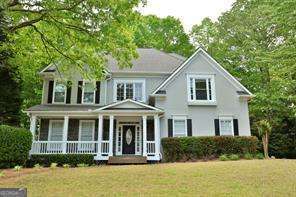 Welcome to this beautifully maintained two-story executive home, ideally located in the sought-after Wyngate at Towne Lake. Enjoy peaceful mornings on the inviting rocking chair front porch, perfect for relaxing and taking in the quiet neighborhood charm. Inside, you'll find an open and airy floor plan with gleaming hardwood floors throughout the main level. The heart of the home is the well-appointed kitchen, offering ample cabinet space, a center island, and a cozy breakfast nook overlooking the backyard. The main floor also features a dramatic two-story living room filled with natural light, a separate den or office space, and an elegant formal dining room-ideal for entertaining. Step outside to a stunning rear deck, perfect for outdoor dining or unwinding at the end of the day. Upstairs, you'll find four generously sized bedrooms and two full baths, including a spacious primary suite with a walk-in closet and private en-suite bath. A full, unfinished basement provides abundant storage space or room for hobbies and workshop needs. The home also includes a two-car garage and is situated near top-rated schools, parks, shopping, and dining-with easy access to I-575 and all that Downtown Woodstock has to offer.