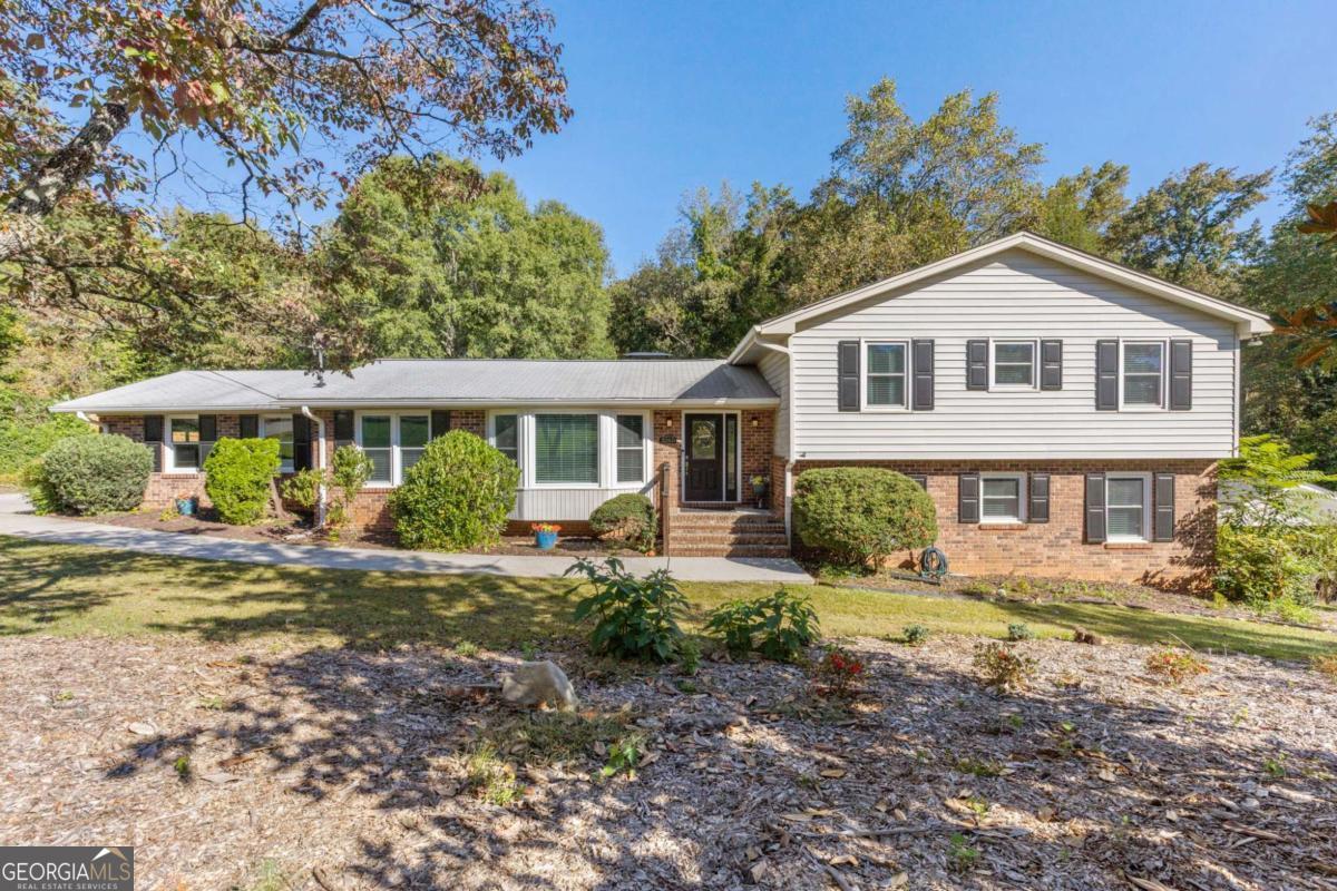 This beautifully updated home in Terrell Mill Estates sits on a private, fenced 1.3-acre lot and features a gunite 18x36 pool with pebble finish, stone coping, new travertine pool deck and artificial turf, along with multiple decks, patios and sunroom. The renovated kitchen offers brand new quartz counters, new appliances and a new sink. The living and dining areas are open concept with real hardwood floors, fresh paint, high ceilings, and a cozy fireplace with gas logs. The primary suite includes a luxurious spa-like bathroom with soaking tub and large shower with new glass enclosure and spacious walk-in closet, and the secondary baths have all been updated. The finished basement provides additional living space with fireplace, kitchenette, dedicated storage area and walk-out access to the pool. A large laundry mudroom with storage and a utility sink adds convenience. A two-car side entry garage, newer driveway and walkway, double-pane windows, fresh landscaping, and easy access to the Chattahoochee National Forest and hiking trails complete this exceptional property.