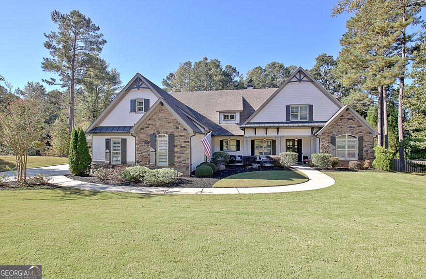 Effortless style and timeless craftsmanship come together in this beautifully designed Northwynn home! Step through the double front doors into a warm, inviting foyer where rich hardwood floors and a wood-planked ceiling set the tone for relaxed elegance. The open layout flows seamlessly into a vaulted great room accented by exposed beams, custom built-ins, and a stacked-stone fireplace. To the left, a formal dining room offers wainscoting, a tray ceiling, and soft natural light filtered through custom wood shutters. The kitchen is a showpiece with timeless white cabinetry, granite countertops, tile backsplash, 36" 5 burner gas cooktop, wall oven, wine cooler, and a generous island with seating. A walk-in pantry/wet bar/mudroom with custom pull-out shelves keeps everything organized and accessible. The serene primary suite on the main level features a tray ceiling with tongue-and-groove detail, a private door to the porch, two closets, and the spa-inspired bath includes dual vanities with granite counters, a soaking tub, and a large walk-in shower with dual heads and a built-in bench, all finished with elegant tilework and bronze fixtures. Upstairs, a spacious bonus room offers endless flexibility: ideal for a media room, additional living area, guest room, or home office, and a large, walk-in attic with spray foam insulation for exceptional storage in a comfortable environment.  The covered patio features a BBQ center with stone surround and natural gas, ceiling fan, and a wall mounted TV for easy entertaining. The vaulted screened gameday porch extends the living area, complete with a floor-to-ceiling stone fireplace, ceiling fan, bistro lighting, and speakers that can connect to a central entertainment system. The oversized three-car dream garage features an epoxy floor and room for vehicles, tools, or a home gym. The beautifully landscaped, private, fenced yard, and picture-perfect curb appeal complete this incredible property. Every space in this four bedroom, four bathroom (plus a bonus!) home has been thoughtfully designed for livability, luxury, and low-maintenance enjoyment, with a location convenient to PTC, Newnan, Senoia, shopping, and dining!