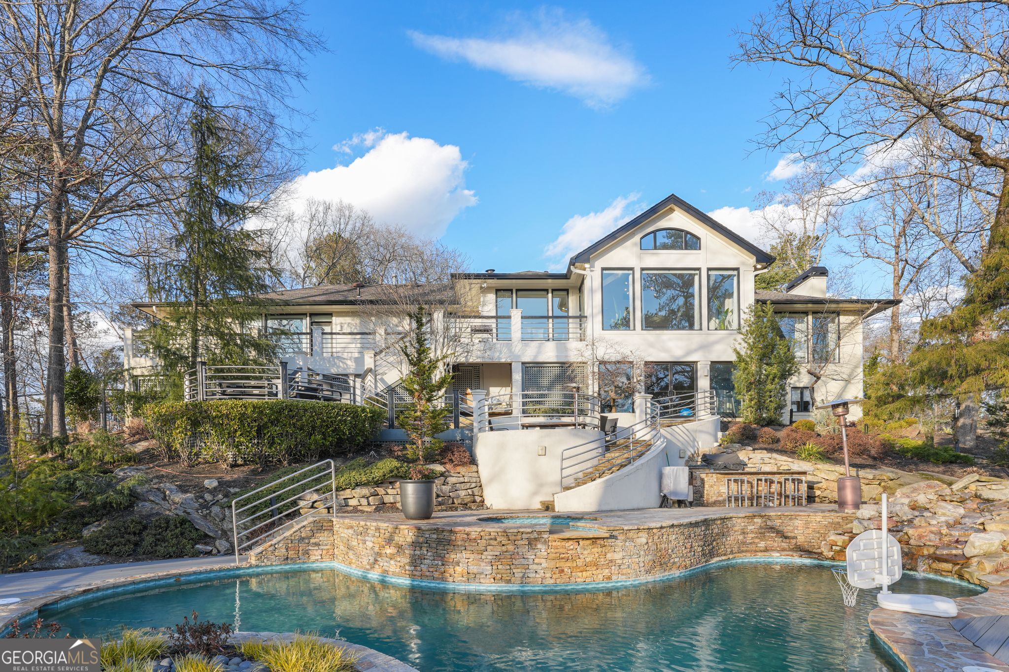 Experience unparalleled luxury and serenity in this beautifully renovated, gated estate, nestled on a quiet private road and surrounded by the breathtaking beauty of the Chattahoochee National Park. Offering true resort-style living, this exceptional home is designed for those who value privacy, elegance, and effortless indoor-outdoor living. Boasting 10- and 12-foot ceilings and expansive windows that flood the interiors with natural light, this estate provides a seamless connection to the lush gardens and tranquil surroundings. The main level features a stunning primary suitecomplete with his-and-hers closets, a steam shower, a soaking tub, and heated floors-a true sanctuary. Two additional en-suite bedrooms, a fireside living room, a family room, and a formal dining room create a perfect balance of comfort and sophistication. At the heart of the home, the chef's kitchen is a masterpiece, featuring an oversized Sub-Zero refrigerator and freezer, a Wolf range and double ovens, a Wolf warming drawer, a Miele dishwasher, a striking waterfall marble island, and sleek porcelain flooring. Designed for both intimate gatherings and grand entertaining, the kitchen is bathed in natural sunlight, enhancing its inviting ambiance. The lower level extends the home's exceptional living spaces with a living room, two additional bedrooms, 2.5 baths, and a stunning screened porch-ideal for relaxation or hosting guests. Every detail of this estate has been meticulously designed for convenience and comfort, including extra-tall and wide doors, three Carrier HVAC systems with Wi-Fi thermostats, a Rinnai tankless water system, and a full-property generator. Outdoors, the estate is equally impressive. Enjoy the heated saltwater pool, effortlessly maintained by an Aqualink app and Zodiac Polaris cleaning system, along with Trex decking, a full irrigation system with drip lines, and dramatic exterior lighting that highlights the beauty of the landscape. A private security gate, full-property security system with exterior cameras, and a spacious parking pad for 5+ cars ensure both convenience and peace of mind. Plus, a brand-new roof is currently in progress! Perfectly situated in the prestigious Mt. Paran - Northside community, this estate offers the ultimate in luxury leasing, combining modern sophistication with natural beauty. Don't miss this extraordinary opportunity to lease a home that embodies privacy, elegance, and unparalleled comfort.