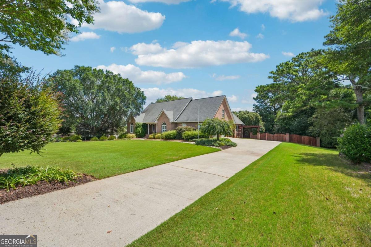 Welcome to your backyard retreat just five minutes from McDonough Square in Henry County's desirable Union Grove school district. This stunning 4-bedroom, 3-bath ranch on a full basement offers a backyard truly built for unparalleled private entertaining. The crown jewel is its custom-designed outdoor paradise: a show-stopping 23,000-gallon gunite saltwater pool with a zero-entry sun ledge, mesmerizing LED lighting, in-pool seating, and a luxurious hot tub with a cascading waterfall. As you arrive, you'll be greeted by a beautifully manicured lawn with established landscaping and a multi-zoned irrigation system, ensuring a vibrant curb appeal year-round. Take a moment to sit and relax under the custom pergola or unwind on the welcoming front porch before stepping inside. Once inside, you'll immediately notice beautiful farmhouse-style distressed hardwood floors throughout the upper level. All three spacious bedrooms on the main level provide ample comfort, while the updated bathrooms boast top-notch custom tile work. The primary shower, with its zero-entry design, dual shower heads, and built-in bench, is thoughtfully crafted for both luxury and accessibility. The living room transforms into your private theater room when the elegant barn doors, adorning the foyer entrance, are closed. A cozy gas fireplace, complete with gas logs, adds warmth and ambiance. The kitchen features granite countertops, stainless steel appliances, and convenient under-cabinet lighting. For more formal occasions, the dining room offers ample space, easily accommodating a baby grand piano or your guitar collection, truly adapting to your lifestyle. Your laundry room is complete with custom cabinetry and a pantry, just steps from the kitchen, and can be discreetly closed off with a sleek sliding glass pocket door - keeping laundry out of sight! Even the garage has been elevated, with a professionally applied epoxy floor and custom wall treatments. As you make your way into the basement, you'll find its own separate HVAC system. It also features a designated workshop area. Outside, the back deck, crafted from exquisite Brazilian IPE hardwood, is truly extraordinary. It's your private oasis. The deck below offers a covered dry zone with a built-in bar, perfectly poised for hosting memorable parties. Just steps away lies your custom-crafted gunite saltwater pool, featuring a zero-entry sun ledge, bubbling LED lights, and plentiful in-pool seating areas with umbrella mounts. Complete with a hot tub and a cascading waterfall, this pool is an absolute showstopper. The custom pump house pavilion, with its dual sliding barn doors and a grand chandelier, matches the adjacent custom cedar pergola, complete with a natural gas fire pit. The pool itself is as smart as it is stunning, including a new variable speed pump, filter housing valve, saltwater cell, and LED lights, for effortless enjoyment. Additional highlights include: Tankless water heater, Laundry with custom cabinetry and pantry, and a 10 x 10 Outdoor Shed to store lawn equipment. Whether you're hosting poolside parties or enjoying a peaceful evening under the stars, this property blends luxury, comfort, and lifestyle like no other.