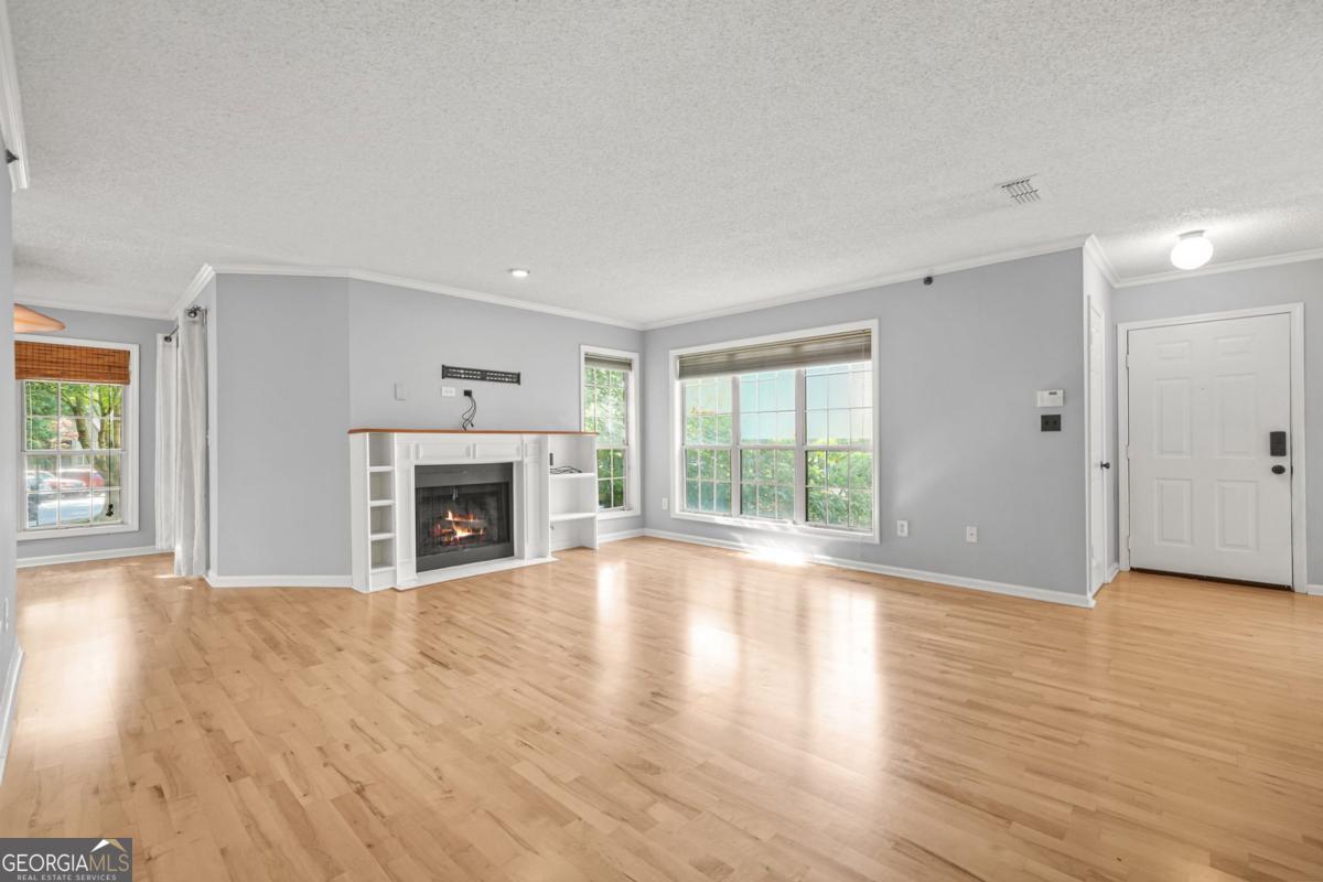 Welcome to 305 Mill Pond Court SE, a beautifully maintained 2-bedroom, 2-bath condo nestled in the heart of Smyrna, GA. Offering 1,379 sq ft of thoughtfully designed living space, this home is filled with natural light, featuring tall windows and hardwood floors throughout. The open concept layout includes a spacious living room with a cozy gas fireplace and a designated dining area just off the kitchen, perfect for entertaining. The kitchen is equipped with stainless steel appliances, stone countertops, oak-stained cabinetry, and a stylish tiled backsplash. Just beyond, a bright and versatile sunroom provides additional space for a home office, fitness area, or lounge, with direct access to a private patio. The oversized primary suite features a walk-in closet and an en-suite bath. Both bathroom features tub/shower combo, tiled flooring and stone-top vanity. Community amenities include serene lake views, a swimming pool, tennis courts, and beautifully landscaped grounds. Enjoy close proximity to Truist Park and The Battery, along with easy access to major highways, top-rated schools, and plenty of shopping and dining options. This condo blends comfort, convenience, and charm in this calm community. With plenty of oppurtunity to customize and make it yours, don't miss your chance to call it home!