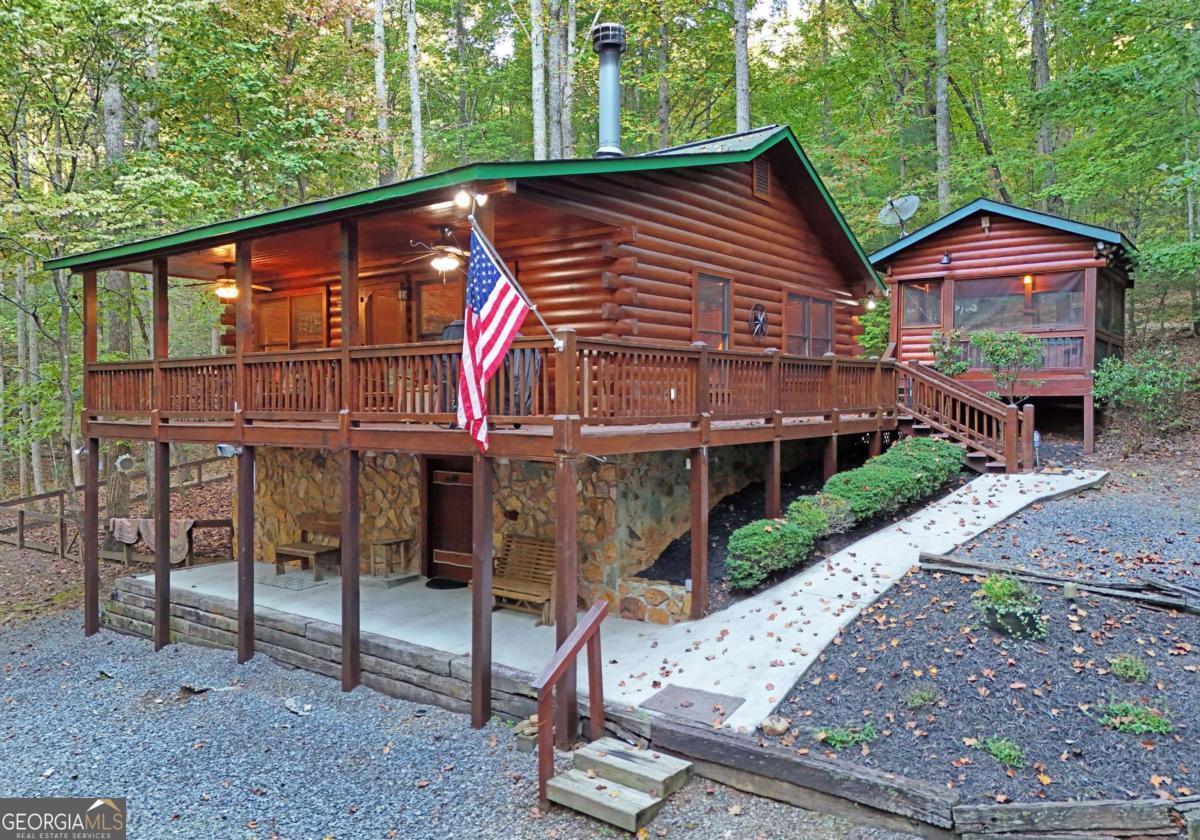 Welcome to this charming cabin nestled in the serene woods, offering a tranquil retreat from the hustle and bustle of everyday life. In the mornings, you are greeted by the soothing sounds of a distant creek. One of the many highlights of this cabin is the separate area dedicated to the hot tub, where you can unwind and relax while surrounded by nature's beauty. Soak in the warm water under a canopy of trees, accompanied by the peacefulness and tranquility of your surroundings. For those who have furry friends, this cabin has a fenced area designed explicitly for worry-free exploration and room to run. In addition to the main living space, there is an additional storage space, with power and insulation on one side and extra storage space on the other side. A parking carport is available for your vehicles. It provides convenience and protection for your cars, ensuring they are shielded from the elements. Inside the cabin, you'll find a charming and cozy atmosphere. The interior is adorned with beautiful wood accents, creating a rustic and inviting feel. The recently updated bathroom boasts modern fixtures, ensuring a comfortable and refreshing experience. This fully furnished cabin lets you move in and start enjoying the peaceful retreat immediately. Every detail is carefully designed to provide an intense and immersive experience of relaxation and tranquility. Suppose you're seeking a getaway surrounded by nature's beauty, with the soothing sounds of a nearby Fightingtown Creek, Benton MacKaye Trail, a dedicated hot tub room, a fenced area for your pets, an additional storage parking carport, and a fully furnished interior. In that case, this cabin is the perfect oasis for you. Take advantage of the opportunity to make this enchanting retreat your own.