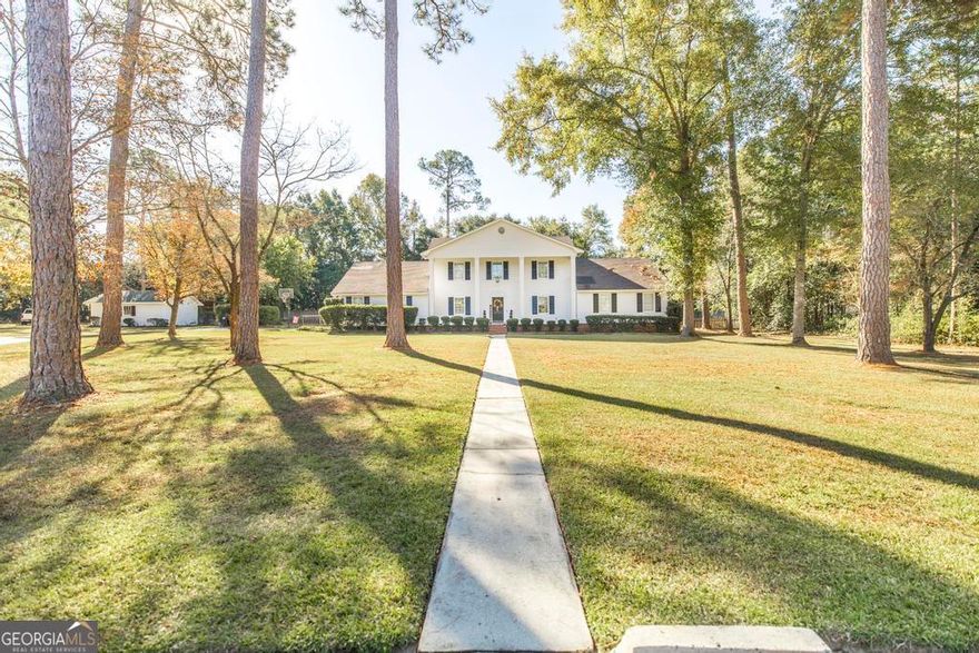 Tucked away in the peaceful cul-de-sac of beautiful Shannon Estates, this stunning Colonial-style home sits gracefully on over an acre of landscaped grounds. A welcoming walkway leads to the grand front porch framed by stately columns-setting the tone for what awaits inside and out.    Step through the front door into a foyer where gleaming hand-scraped hardwood floors draw your eye to the showstopping brick fireplace-open to both the living room and kitchen for the perfect blend of warmth and connection. The expansive living room flows effortlessly into a cheerful breakfast area where large windows frame a perfect view of the sparkling pool. The kitchen offers generous counter and prep space, a breakfast bar, and newer appliances that make entertaining easy and everyday meals a joy.    A formal dining room, guest powder room, and large laundry room with sink and storage are conveniently located near the garage entry.    The primary suite on the main level feels like a retreat-complete with a coffee or wet bar, private door to the covered patio, and a spa-like bath featuring a stunning tiled shower, jetted tub, dual vanities, and two walk-in closets.    Upstairs you'll find three additional bedrooms, a full bath, and a versatile flex room that opens to a spacious bonus room-perfect for a home office, media room, or hobby space.    Outside is where this home truly shines. The backyard is designed for gathering and relaxing, featuring a beautiful covered patio with a porch swing, a covered grilling area, and a fantastic in-ground pool ready for summer fun. A detached workshop with bay door and lean-to offers even more space for projects, storage, or outdoor equipment.    If you're looking for a home that offers timeless charm, generous space, and a backyard meant for making memories-107 Quinn Drive delivers it all.