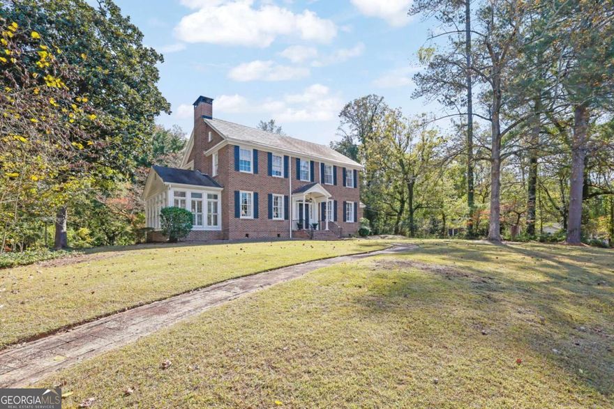 120 Jeanette Street is a rare blend of architectural pedigree, craftsmanship, and tranquility - where classic Georgian design meets timeless Southern living. Designed in 1929 by Ivey & Crook, one of Atlanta's most respected architectural firms, this distinguished residence exemplifies the Georgian Revival style - perfect symmetry, balanced proportions, and understated elegance. Constructed of rich red brick with contrasting black shutters, the facade presents a stately yet welcoming presence. A columned portico with fluted supports and a triangular pediment frames the front door, adorned with original sidelights and a delicate fanlight transom - glowing in afternoon sun and setting the tone for the craftsmanship within. A brick walkway winds through the front lawn, softening the symmetry and leading to the entrance. Mature trees, sweeping lawns, and thoughtful siting on three acres create a sense of quiet grandeur - spacious yet intimate. At the rear, a charming pool and pool/guest house with 1 bedroom and 1.5 bath offer a relaxed counterpoint to the home's formality, ideal for entertaining or private retreat. Inside, graceful proportions, sunlight, and original details define the interiors. The central foyer showcases hardwood floors, intricate moldings, and a sweeping staircase that rises with understated elegance. Flanking rooms - a bright formal living room centered on a carved mantel and a balanced dining room overlooking the lawn - reflect Ivey & Crook's mastery of flow and proportion. To one side, the formal living room centers on a traditional fireplace with a carved mantel and flanking windows that fill the space with natural light. The dining room on the opposite side mirrors this sense of proportion - bright, balanced, and open, with original millwork and double windows that look out to the beautiful lawn. Together, these rooms create an ideal setting for both entertaining and quiet evenings. The kitchen, filled with morning light, retains its vintage footprint and offers potential for sensitive modernization. Adjoining rooms provide inviting informal spaces, including a breakfast room with original glass-front cabinetry. Upstairs, four bedrooms continue the home's timeless symmetry, with high ceilings, ample windows, and 1920s craftsmanship. Light shifts beautifully throughout the day, and two and a half baths serve the upper and main levels. The basement, with original plumbing and electrical connections, includes a long-unused bath - a glimpse into the home's early design foresight. It offers flexible space for storage, a workshop, or future renovation. The three-acre property unfolds gently around the home, with manicured lawns, mature magnolias, and a natural sense of privacy. The pool and pool house, added later, harmonize beautifully with the landscape, giving the estate a quiet, resort-like quality. Lovingly cared for by only two families since 1929, this home stands as a living testament to Ivey & Crook's enduring Southern grace, proportion, and light.