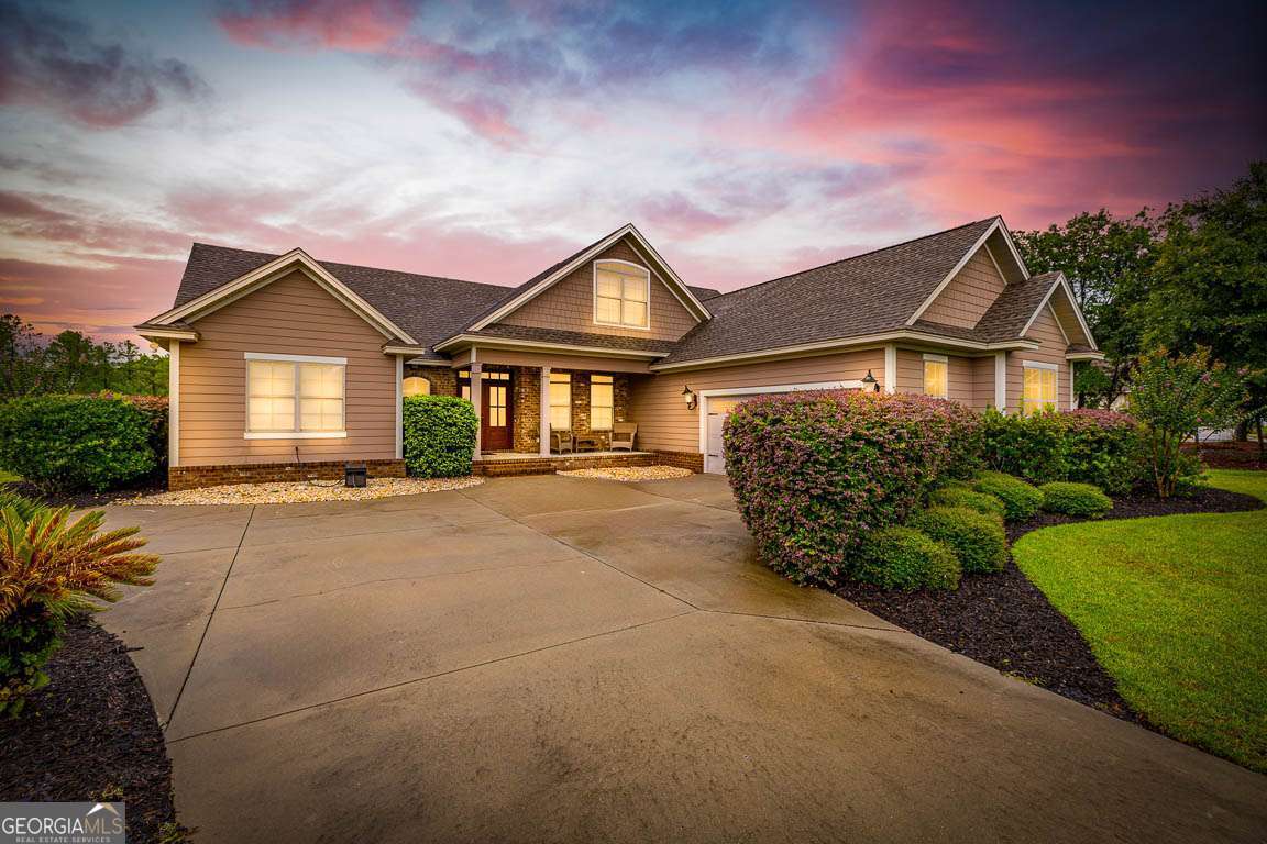 This beautifully maintained 5-bedroom, 3.5-bath home sits on a scenic 0.46-acre lakefront lot in a desirable gated neighborhood. The home welcomes you with a spacious foyer and features tile flooring throughout the main living areas, with luxury vinyl plank (LVP) in the guest bedrooms and carpet in the primary suite. The open-concept kitchen is ideal for both everyday living and entertaining, boasting a breakfast area, breakfast bar, center island, custom cabinetry, stainless steel appliances, and a pantry. Adjacent to the kitchen are a formal dining room, a cozy living room with a fireplace, and a versatile family room/flex space. The primary bedroom suite offers comfort and privacy, complete with an ensuite bath featuring dual vanities, a separate tiled shower, a jacuzzi tub, and a large walk-in closet. Also on the main floor is a guest bedroom, a half bath, and a laundry room equipped with a washer, dryer, sink, and an oversized storage closet under the stairs. Upstairs you'll find additional guest bedrooms and a full bath, providing ample space for family or guests. The home's exterior is finished in durable Hardi siding, and includes a carriage-style garage and a screened porch overlooking the serene lake. Located near schools, shopping, I-95, and the North Glynn Sports Complex, this community also offers resort-style amenities including a pool, lounge area, fire pit, and grilling station, making it the perfect place to call home.