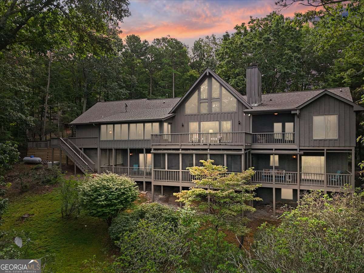 Welcome to 188 Tea Berry Lane, where modern comfort meets mountain serenity in the heart of Big Canoe. Perfectly positioned to capture breathtaking panoramic views of Mt. Sanderlin, Mt. Oglethorpe, and Mist Mountain, this beautifully updated home blends mountain charm with luxurious upgrades, creating a lifestyle that feels like a retreat every day. Step inside to a vaulted great room with stunning beamed ceilings, filled with natural light, rich wood accents, and a stunning stone fireplace - the perfect gathering space where breathtaking mountain views take center stage. The chef's kitchen has been thoughtfully renovated with custom cabinetry, granite countertops, and upscale appliances, creating a perfect space for cooking and entertaining. The open layout flows effortlessly into a dining space that comfortably seats 12+, making it ideal for hosting family and friends. A sunroom framed by walls of glass captures panoramic views of the mountains and valleys, creating a cozy, light-filled retreat for morning coffee or quiet evenings surrounded by nature. The primary suite is a serene escape featuring two spacious walk-in closets and a newly renovated Bluetooth-enabled bathroom with a spa-style shower and dual vanities. Step out to your private screened porch and unwind as you breathe in the peaceful mountain air. Upstairs, the loft offers one of the home's most dramatic perspectives, showcasing an elevated view of the surrounding peaks and valleys - an ideal spot for a reading nook, home office, or private retreat. The terrace level expands your living space with a recreation room, private guest accommodations, and a fully equipped workout area. Both bedrooms on this level offer direct access to their own private decks, creating serene retreats for guests to enjoy the fresh mountain air. Outside, it's rare to find a home that combines panoramic mountain views with a usable backyard - perfect for gathering, gardening, or simply enjoying the outdoors. Five decks, including two screened porches, provide endless opportunities for dining, entertaining, or relaxing while taking in the scenery. Meticulously maintained with over $150,000 in upgrades, including two new HVAC systems, new recirculating hot water heater, refinished decks, fresh exterior paint, repaved/widened the level driveway, whole-house generator and much more. Brand-new carpet throughout the terrace level, loft, and sunroom, ensuring a move-in-ready experience. Living in Big Canoe offers more than a home - it's a lifestyle. This one-of-a-kind, vibrant Blue Ridge Mountain private community offers over 20 miles of hiking trails, 3 waterfalls, 3 pristine lakes, 27 holes of championship golf, and over 50 community clubs, creating endless opportunities for recreation and connection. Residents enjoy a newly remodeled clubhouse with multiple dining options, 3 swimming pools, pickleball and tennis courts, a state-of-the-art fitness center, and access to scenic overlooks and natural preserves. As a designated wildlife sanctuary, Big Canoe provides the rare opportunity to live surrounded by nature while enjoying resort-style amenities. Whether you're seeking a lucrative short-term rental opportunity or your own private mountain retreat, this home delivers unmatched potential and value.