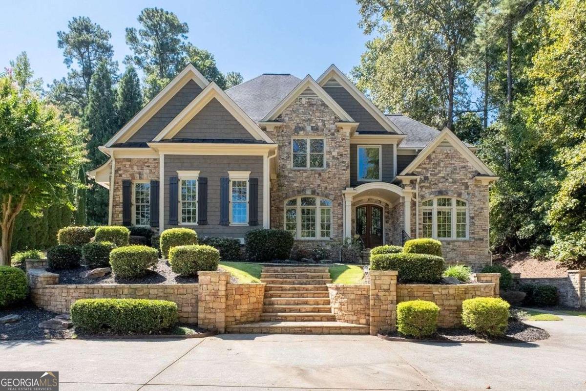 Tucked away at the end of a private, tree-lined drive in one of the area's most exclusive communities, this custom-built lakefront estate offers an extraordinary blend of luxury, seclusion, and breathtaking beauty. Set on over an acre of professionally landscaped grounds, the home features six spacious bedrooms and six elegant bathrooms, with an open-concept design that floods the interior with natural light and showcases upscale finishes throughout. The gourmet chef's kitchen, complete with premium appliances and bespoke cabinetry, flows seamlessly into a gracious keeping room and sunlit breakfast area. The main-level primary suite is a private sanctuary with its own fireplace, spa-inspired bath, custom walk-in closet, and direct access to a covered porch overlooking serene lake views. A fully finished daylight basement includes a private home theater and expansive living space, all freshly painted and designed to capture the tranquil surroundings. Outdoors, enjoy an extended stone patio, mature trees, and a lush backyard that opens to the water-perfect for entertaining or peaceful reflection. Impeccably maintained and move-in ready, this one-of-a-kind retreat offers timeless craftsmanship, modern comfort, and a resort-like lifestyle near top-rated Roswell and Cobb County schools, fine dining, and commuter routes.