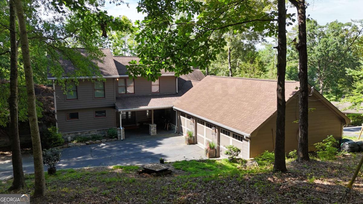 Experience the ultimate Lake Lanier lifestyle in this spacious and thoughtfully designed and fully renovated home, tucked away in a private, wooded setting just steps from your own 24x24 single-slip party dock with room to upgrade to a Corp approved 32x32 slip. With lake views and direct water access, you can go from boat to back door in under a minute-making this home a dream for entertaining, relaxing, or short-term rental potential. Enjoy worry free living with recent upgrades like brand-new roof, tankless hot water heater, and white oak site finished flooring. The main level features a luxurious primary suite, soaring vaulted ceilings in the living room, a dedicated office, and a chef's kitchen that flows effortlessly into a keeping room and an oversized dining area that seats up to 20 guests. The kitchen boasts a 48" GE Monogram range, Electrolux oversized side by side refridgerator and freezer, as well as a walk-in pantry and additional cabinet pantry storage with pull out drawers. Also on the main level: a well-placed laundry room for convenience and functionality. A built-in Sonos speaker system runs throughout the home, delivering rich sound for entertaining or enjoying your favorite playlist in every room. Upstairs offers two additional bedrooms and a full bathroom, while the fully finished basement expands your living space with two more bedrooms (one currently being used as a gym), two full baths, a spacious media room/living area is perfect for game day or cozy movie nights and still leaves room for ping pong, card table or your game of choice. Step outside to enjoy the peaceful North Lake Lanier surroundings from your covered patio-ideal for morning coffee or evening cocktails. Rinse off after a day on the lake in the outdoor shower, and take advantage of the oversized 3-car garage for all your lake toys, vehicles, and storage needs. The turf backyard is the perfect set up for endless games of cornhole. Whether you're searching for a full-time residence, weekend getaway, or short-term rental investment opportunity, this property offers space for everyone and every occasion. Conveniently located just off GA400 and minutes from the Dawsonville Outlets, Publix, Kroger, and more-yet surrounded by nature and serenity.