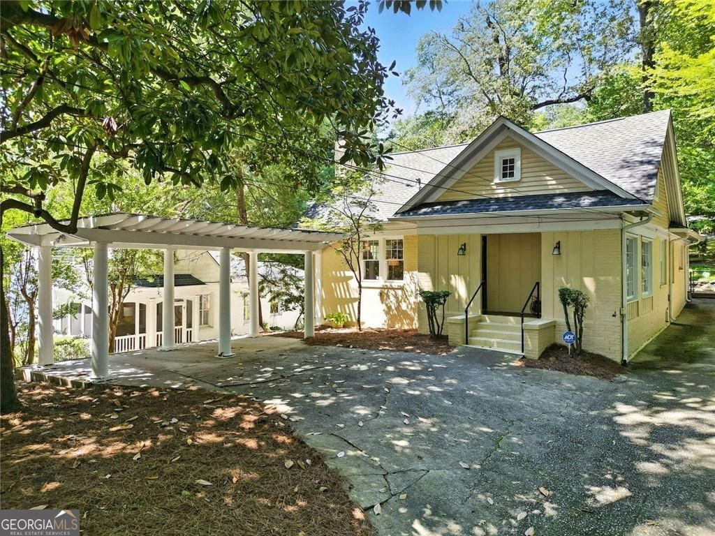 Tucked beneath mature trees in sought-after Peachtree Heights, this 1930s Craftsman pairs original character with thoughtful updates and wooded privacy, right in the heart of Atlanta. Step through the front door into a sun-filled living room anchored by a white brick fireplace and flanked by built-ins. From there, move into the adjacent sitting room, ideal for reading or conversation, and then into a formal dining room that connects seamlessly to the kitchen. The kitchen keeps things efficient with solid-surface countertops, dark-stained cabinetry, and a gas range, plus a dedicated pantry and nearby mudroom for smart storage and daily function. Two main-level bedrooms sit quietly toward the back of the home, each with its own closet and easy access to a full bath. A rear-facing sunroom with a wall of windows creates a flexible space for work, play, or afternoon naps. Head upstairs to discover a spacious primary suite that feels like a true retreat. The oversized bedroom flows into a massive walk-in closet-more than 25 feet deep and a full bath with skylights, dual vanities, and a soaking tub tucked under a sloped ceiling for added charm. Downstairs, an unfinished basement gives you room to expand, store, or create. Outside, a terraced backyard with native landscaping invites slow mornings on the deck or evenings spent entertaining. A covered carport and long driveway offer plenty of off-street parking. All this, just minutes from Midtown, Buckhead, dining, shops, and parks, yet surrounded by trees and timeless character.