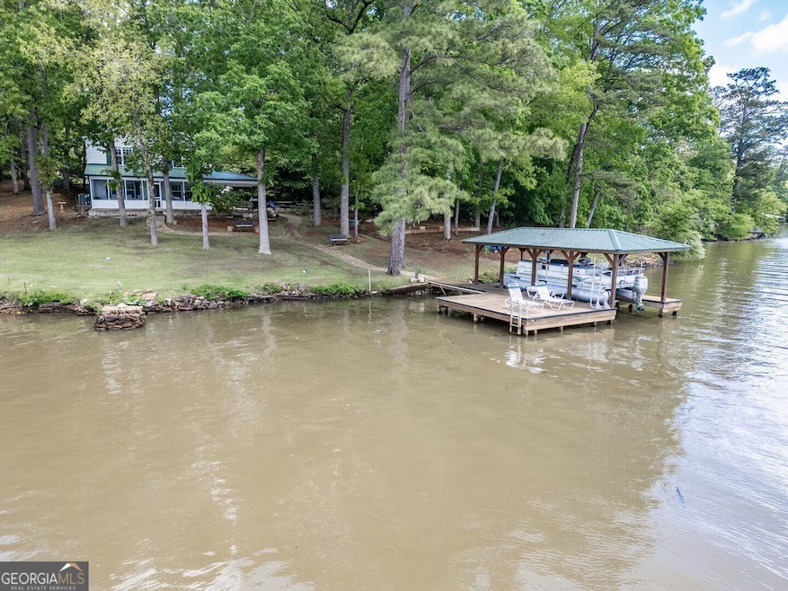 Come to Jackson Lake and experience this incredible property boasting over 550 feet of pristine water frontage. Thanks to its unique location, you'll enjoy a refreshing breeze even on the warmest summer days, making every moment by the water even more enjoyable. Centrally located with panoramic views and breathtaking sunsets, this is the perfect lakefront escape. The gently sloped lot offers an easy walk to your covered stationary dock, complete with a boat lift and a swim area. The home features a charming screened porch with ceiling fans-an ideal spot for relaxing and soaking in the peaceful surroundings. Inside, the open-concept design connects a large kitchen and breakfast area to the spacious great room, highlighted by a wall of windows overlooking the lake and large screened porch. The main floor offers two ample bedrooms and a large bathroom, while upstairs you'll find four additional bedrooms and a full bath, providing plenty of space for family and guests. The property includes two outbuildings, perfect for storing lake toys and equipment, and a water pump at the dock for drawing lake water. Expect to spot a bald eagle perched outside your living room window-it's part of the everyday magic here. Located at the very end of Campbell Road, there's no through traffic, ensuring privacy and a peaceful atmosphere. Sprawling between you and your neighbors, the property is adorned with massive pine and hardwood trees that provide welcome shade during summer afternoons while the family enjoys the beautiful yard and swimming area. The water depth at the dock ranges between eight and twelve feet, perfect for all your lake activities. Designed for entertaining, this home offers spacious indoor and outdoor areas, with an abundance of windows bringing natural light and stunning lake views into every room. The owner has already had the property professionally inspected and completed all identified repairs-this home is truly move-in ready. Come visit and see why you might never want to leave! We look forward to welcoming you to the lake.