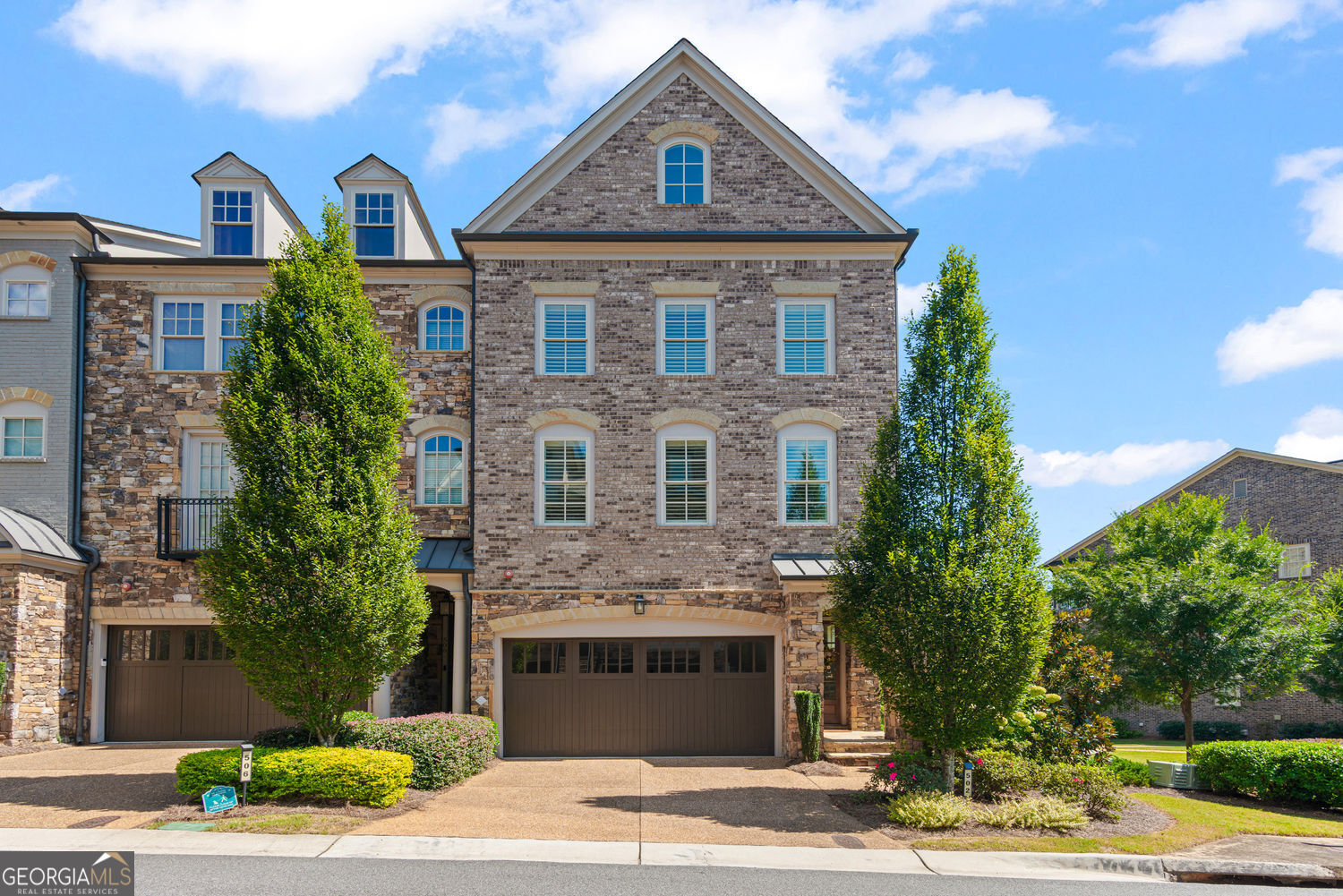 Surrounded by greenery and tucked behind the gates of Abbington at Wildwood, this JW Collection townhome offers a rare blend of comfort, design, and convenience. Crafted with timeless detail and modern ease, it's a true retreat just minutes from Truist Park, The Battery, and scenic river trails and quick access to I-75 and I-285. This home has been gently lived in and offers the fresh feel of new construction. Inside, a private elevator seamlessly connects all four levels, while a two-step entry from the garage leads into the heart of the home. The main level showcases a chef's kitchen with Thermador appliances, a warming drawer, double-stacked soft-close cabinetry with integrated organization, a walk-in pantry, wine cooler, and an oversized breakfast bar. This level also offers a formal dining room, powder bath, drop zone, and coat closet. The layout flows to a generously sized deck, perfect for entertaining or relaxing outdoors. Throughout the home, thoughtful finishes such as designer paint colors, upgraded lighting, custom drapery, plantation shutters, and an additional Rheem water heater enhance everyday living. Upstairs, the expansive primary suite offers a peaceful retreat with a sitting area, dual walk-in closets, and a spa-inspired bath with soaking tub, His-n-Hers vanities, closets and water closets. A spacious ensuite bedroom and daylight laundry room with Samsung appliances and built-in storage complete the level. The top floor is designed for year-round enjoyment, with a covered patio featuring a stone fireplace and mounted TV, plus a game room with wet bar and private guest suite. On the terrace level, enjoy a game room, hidden storage behind a custom bookcase, flexible space and an additional private patio open to a fenced green space perfect for play space or furry friends. Positioned on one of the community's largest end-unit lots, the home backs to lush woodlands with private trail access to Cochran Shoals and the Chattahoochee River. Community amenities include a private park with fireplace, fenced dog area, and ample guest parking right at your front door.