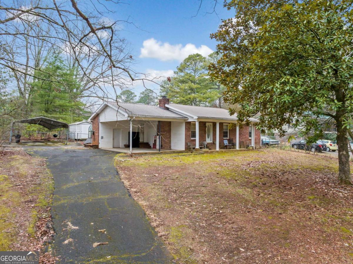 Investor opportunity near downtown Jasper! This classic brick ranch offers three bedrooms, two bathrooms, and plenty of potential. A metal roof, newer vinyl windows, and a recently updated HVAC system provide a solid foundation for future improvements. Inside, the home features a spacious living room with a brick fireplace, a formal dining room or optional den, and a sunroom with backyard views. The kitchen has stainless steel appliances and original wood cabinetry, ready for a modern refresh. The primary bedroom boasts vaulted ceilings with exposed beams and private access to the backyard. A covered carport and extra storage buildings add convenience, while an additional lot is available for expansion. With its prime location and great bones, this property is an excellent opportunity to add value and build equity!