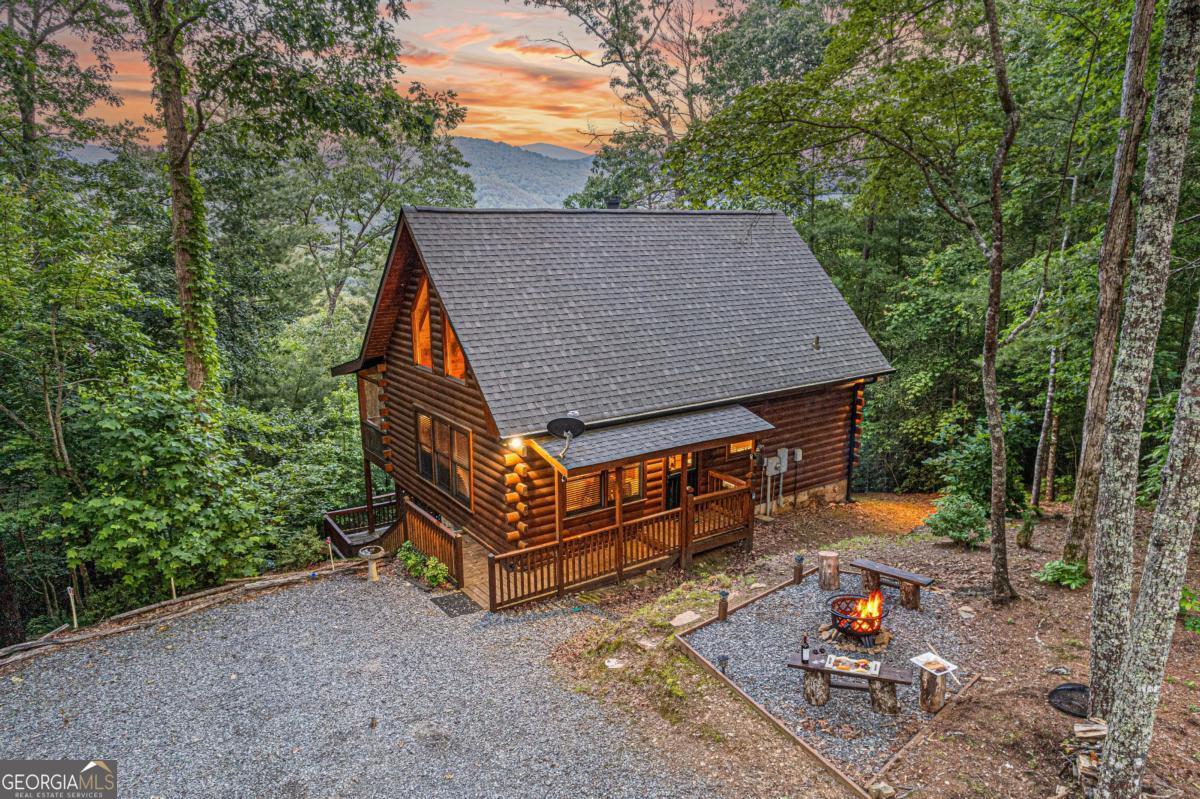 Searching for the perfect mountain retreat? This fully furnished 2BR/1.5BA true log cabin offers breathtaking year-round mountain views and embodies the charm of the North Georgia Mountains. Whether you're looking for a vacation getaway or a forever home, this highly successful rental cabin is a fantastic choice. Tucked away in a private, picturesque setting, the cabin greets you with a covered porch leading into an inviting open-concept living, dining, and kitchen area with vaulted beamed ceilings. Gorgeous pine flooring, walls, and ceilings add to its rustic charm, while large windows bring in abundant natural light. Cozy up by the gas log fireplace or cook with ease in the well-equipped kitchen featuring stainless steel appliances. The main floor boasts a convenient laundry closet, a master bedroom, and a full bath. Step outside to a spacious screened-in porch-perfect for enjoying the mountain views or unwinding in the hot tub. Upstairs, a generous loft serves as a second bedroom with a half bath. The lower deck provides extra storage and more stunning mountain vistas. With a brand-new HVAC system and fully furnished interiors, this cabin is truly move-in ready. Granite counters to be installed soon! Ideally located near hiking trails, wineries, tubing, rafting, shopping, and dining, it's just a short drive to downtown Ellijay and Blue Ridge. Don't miss this incredible opportunity!