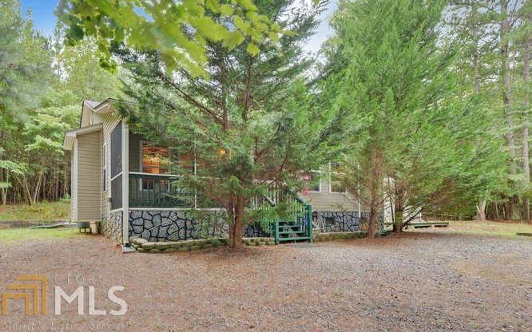 Just beyond the Trees! This Easy One Floor Living, 2 Bedroom 2 Bath Ranch Home in Gated Resort Community is just where you want to be in the North Georgia Mountains. From the Welcoming Screened Front Porch into the Spacious Great Room with Rock Fireplace into the Large Eat in Kitchen with Custom Cabinets and lots of Counter space, All Appliances Remain. You’ll Love the additional Living Space in the Multi-Seasonal Sunroom with Grilling Deck just outside. Master Bedroom with In-Suite Full Bath, Tile Floors and more. Second Bedroom, Hall Bath and Large Laundry Closet with additional storage. Tons of Extra’s too: Furnishings are Negotiable, Sunroom with Custom Blinds & Ceiling Fan with Heater (you just don’t see those around). Generator Shelter, Great Storage Building Shop with Power. All Electric with Gas Log Fireplace. Double Lot Already Combined with the Association gives you .91 acres. All paved road for added convenience. Resort Amenities Include 3 pools (One covered for year round swim) Tennis, Fitness, Pickleball and much more.