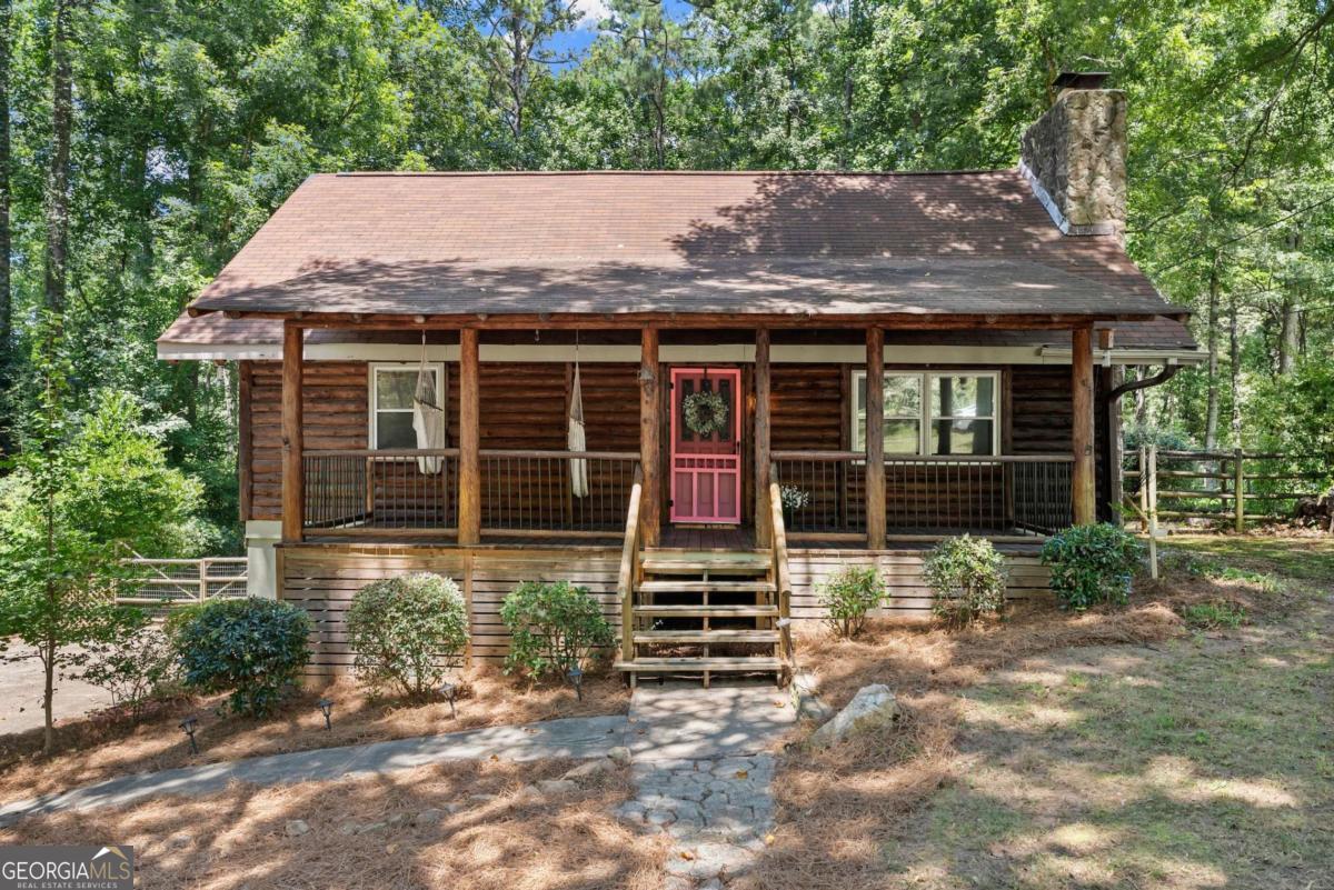 Rustic Charm Meets Prime Location - Minutes from Downtown Woodstock! Dreaming of log cabin living on one of the LARGEST lots in the neighborhood-without giving up the convenience of a vibrant suburban lifestyle? Welcome home to this beautifully maintained 3 bedroom, 2 bath log cabin, perfectly situated on nearly an acre within the city limits of Woodstock, JUST 2.6 miles from Downtown! From the moment you arrive, you'll be drawn to the generous rocking chair front porch, perfect for relaxing and enjoying the peaceful surroundings. In addition, the spacious back deck offers serene views of Corps of Engineers land-which will never be built on-giving you a rare level of privacy and a true sense of being tucked away in nature. Whether you're hosting a BBQ or enjoying your morning coffee, this outdoor space is designed for both relaxation and entertaining. Inside, the home features a stunning two-story great room with warm log finishes and timeless fixtures that capture the cozy, cabin aesthetic. The inviting country kitchen is complete with painted cabinets, a charming tile backsplash, a gas stove, and built-in pantry. The property includes a spacious drive-under garage and an unfinished basement, offering ample room for storage or future expansion. A 12'x28' shed provides the perfect space for a workshop, boat storage, or additional gear. And with no pesky HOA, you can bring your RV, boat, and all your toys with no restrictions! Located just minutes from shopping, restaurants, breweries, Dupree Park, and more. This truly is a rare opportunity to own a home in a sought-after location with award-winning schools-all without having to pay costly HOA fees. Run, don't walk, to see this stunning property in person.