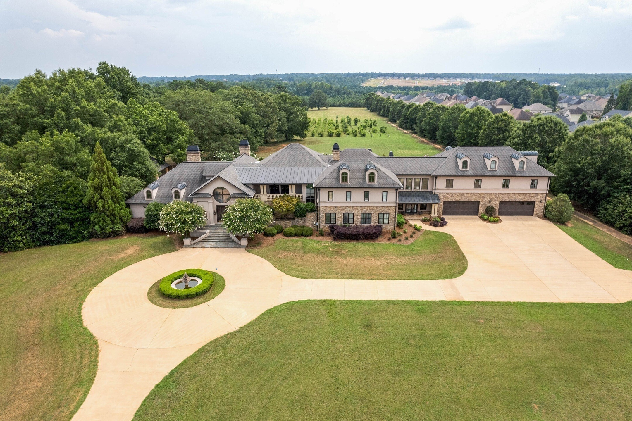 Welcome home to the exclusive DEERFIELD ESTATE. From the gated entrance and grounds of this Magnificent 12,200 sq. ft. European Style Masterpiece to the unparalleled elegance, luxury and grandeur of the interior, you will be enchanted! Property fully renovated in 2000. Spanning 3 levels, this home offers 6 stunning bedroom suites and 8 bathrooms, and is situated on 50 acres of level land creating a park-like setting with 2 lakes and a private Vineyard. Sheer opulence awaits just beyond the front entrance. As you enter the main level, you are greeted by the Grand 2-story foyer with sweeping spiral staircase, soaring ceilings with both stained glass & vertical windows that drench the home in natural light, above the glistening tile and inlaid hardwood floors of the echoing corridor. Marble columns frame a sunken Grand gathering room with fireplace and built ins which flow into the elegant, banquet size dining room and in to the gourmet kitchen with breakfast room and keeping room with coffered ceiling and stacked stone fireplace. Main level also boasts multiple butlerCOs pantries, a separate staff kitchen and laundry as well as a concession area to service the Home Theatre and offers access to the 4 car garage and incredible outdoor entertainment spaces. The exquisite primary suite is also on main level with tray ceiling, double sided fireplace and an ensuite with tile, luxurious soaking tub, separate dressing room, multiple vanities and walk in closets, and a morning room with coffee bar and fireplace with access to pool and entertainment space out back. The 2nd level offers an open study space and piano nook, a recreation/gym or billiard room and a guest or Au Pair Bedroom Suite with bath and kitchen. There is also an elevator that services each floor. 2nd floor further boasts 4 more Bedrooms each with their own spacious ensuite and access to an exterior covered 2 story veranda. Rounding out the interior of this incredible home, is the 3rd floor which features the vaulted 6th bedroom and full bath. *Exterior grounds of home features incredible outdoor entertainment space with resort style lap pool flanked by a pool house on one side and outdoor kitchen, bar and grill pavilion on the other. Not to mention, home is nestled on 50 lush, level acres of land with 2 pristine Lakes and a bountiful, working Vineyard. Property is perfect for hosting large scale grand events with family and friends as well as enjoying small, intimate outdoor relaxation set to the backdrop symphony of birds, butterflies and wildlife. *Property would also make a perfect Wedding Venue, Bed & Breakfast or Golf course. Conveniently located only 20 mins from Atlanta Airport.