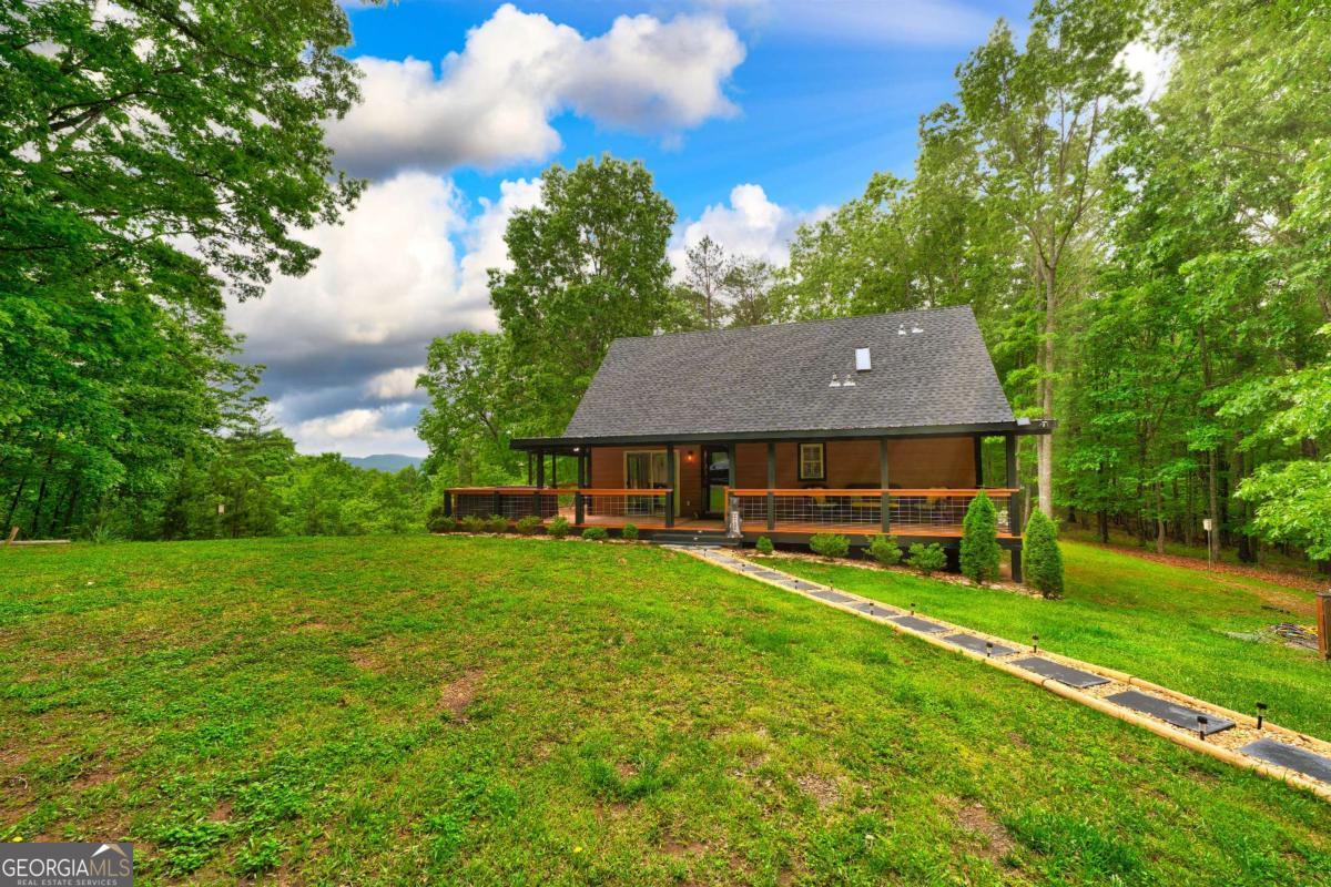 Experience the best of Georgia mountain living just steps from the North Carolina border in the tranquil Timber Wood community of Mineral Bluff. Currently a successful vacation rental, this inviting craftsman-style cabin offers 2 bedrooms and 2 bathrooms across 1,296 square feet. Situated on a generous 3.29-acre lot that includes two parcels, one of which is buildable to easily add a second home or accessory structure such as a barn, barndominium or whatever you can dream up! Enjoy sweeping, year-round mountain views from the wraparound porch, which features a screened section and a hot tub-perfect for relaxing in any season. The home sits on level terrain and boasts a cozy, well-maintained interior that blends classic charm with modern comforts. Updates include NEW roof, NEW composite siding, NEW decks and rails, NEW washer and dryer, and a tankless water heater. Outdoors, an inviting fire pit provides the perfect location to enjoy the beautiful long-range mountain view. Conveniently located to Blue Ridge, Blairsville, and Murphy, NC, you can enjoy a wide range of activities, including hiking, boating on Lake Nottely and Lake Blue Ridge, visiting local casinos, and discovering unique shopping and dining experiences. This property is ideal for those seeking a peaceful mountain retreat or investment property with both privacy and proximity to local attractions.
