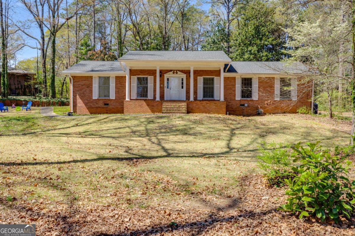 HUGE PRICE IMPROVEMENT! LET'S SAY WELCOME HOME! An all-brick ranch home offers timeless charm and unbeatable convenience! Perfectly situated on a private, one-acre lot within walking distance to downtown Douglasville, this well-loved home boasts 3 bedrooms, 2.5 baths, and an impressive amount of square footageCoall on one level. Step inside to a welcoming foyer that wows with a full wall of custom cabinetry for all your storage needs and built-in bookshelves that elegantly separate the foyer from the oversized living room. The open-concept flow continues into a huge dining room featuring a large pantry closet, perfect for hosting gatherings. The kitchen exudes a delightful retro charm with abundant cabinetry, an oversized island/bar for entertaining, and seamless connectivity to the spacious family room, complete with a cozy brick fireplace and additional built-ins. Retreat to the expansive ownerCOs suite, offering an impressive four closets and an ensuite bath. Two generously sized secondary bedrooms share a Jack-and-Jill bath, each featuring ample closet space. A wide hallway lined with additional storage, a separate laundry room, and a convenient kitchen-level entry from the carport add to the home's functional appeal. The property also includes a partially finished crawl space with a concrete floorCoideal for a workshop, plus an outbuilding in the backyard for additional storage. Enjoy peaceful evenings grilling on the back patio or customizing the private, wooded lot to fit your outdoor vision. Don't miss this opportunity to own a well-built home with incredible potential in a prime locationCojust minutes from I-20, restaurants, shopping, and the hospital! SELLER WILL OFFER A CARPET ALLOWANCE!