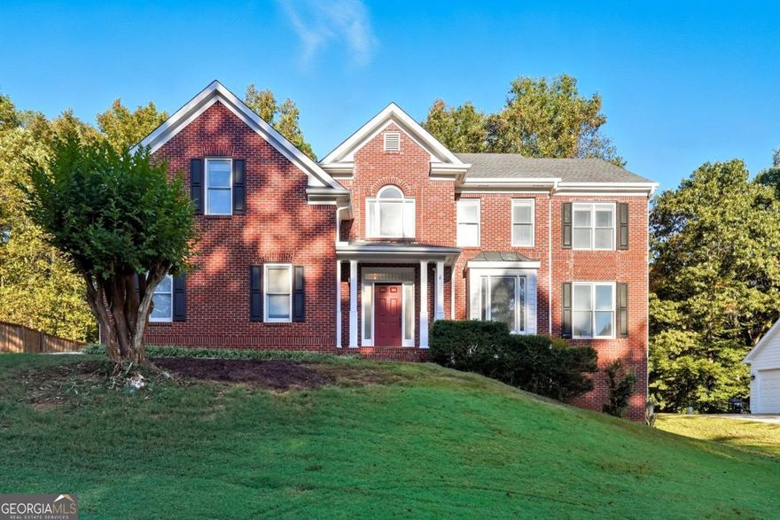 Discover timeless elegance and modern comfort in this beautiful brick home located in The Hamptons Grant, - a quiet, tree-lined community known for its timeless curb appeal and ideal Alpharetta location, with Forsyth Taxes.  Near Avalon, Halcyon, downtown Alpharetta, and top-rated schools, this property combines classic craftsmanship with the conveniences of today's luxury living.  Step into a bright two-story foyer with gleaming hardwood floors and a striking wrought-iron staircase. The open floor plan flows effortlessly through the formal living and dining rooms into a spacious family room filled with natural light and centered around a cozy brick fireplace - perfect for everyday living and entertaining.  Enjoy the sunny breakfast nook framed by bay windows overlooking the backyard. The kitchen features granite countertops, stainless steel appliances, custom white cabinetry, and a butler's pantry.  A laundry room with built-in sink and a half bath on the main floor add everyday convenience, making this home as functional as it is elegant.   Upstairs, retreat to the large primary suite with tray ceilings and sitting area. The spa-inspired bathroom offers a soaking tub, glass-enclosed shower, and dual vanities. Create a closet oasis in the immense primary walk-in closet with natural light. Three additional bedrooms provide ample space for family, guests, or a home office.  The daylight basement offers incredible potential for a home theater, gym, playroom, or in-law suite and features direct exterior access.  Enjoy outdoor living on the expansive back deck overlooking a private, tree-lined yard - ideal for morning coffee or weekend gatherings.  Located on a quiet street with mature landscaping, this move-in-ready Alpharetta home is just waiting for your custom touch.