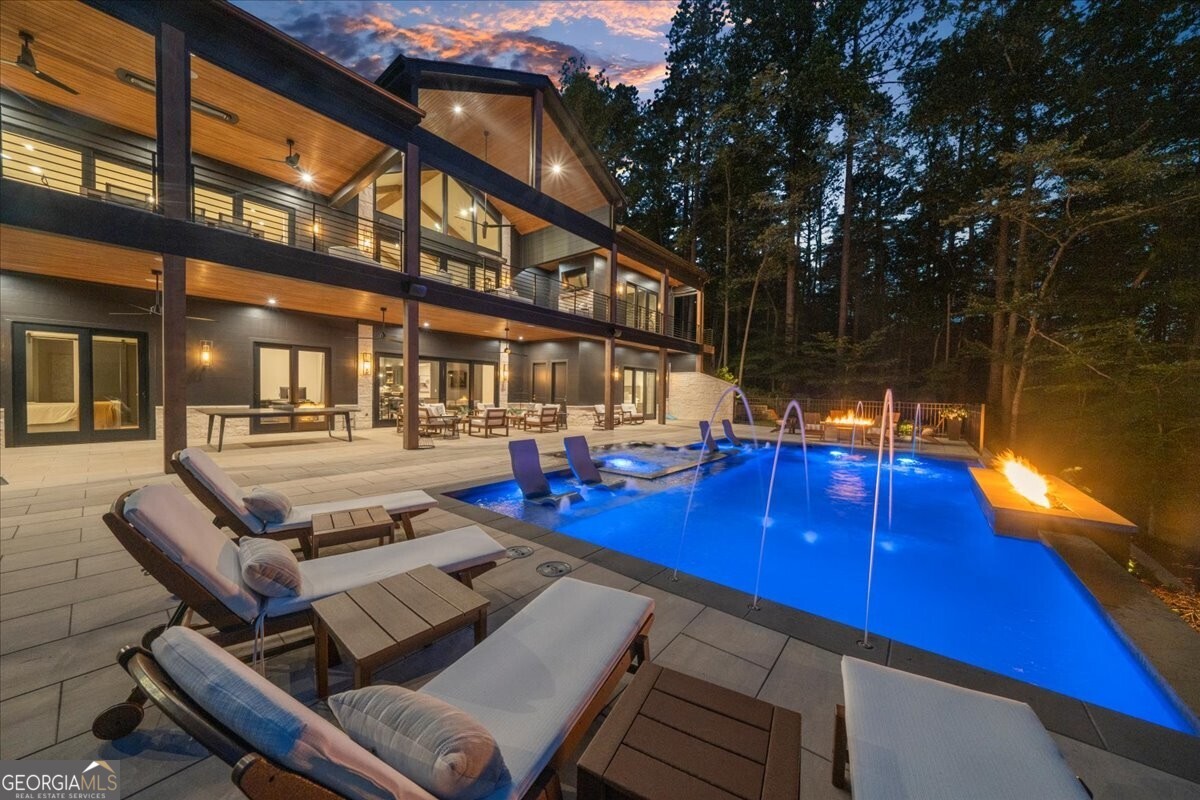 Looking for a brand-new luxury home on Lake Lanier with breathtaking views, a heated saltwater pool, and a deep-water dock? This newly constructed (2022) masterpiece delivers everything you've been dreaming of and more! Situated on a private point lot with the property line nearly in the water, this home boasts a rip rap shoreline, a beach, and two sides of CORPS property, offering privacy and direct access to the lake's incredible amenities. Step inside to over 7661 +/- square feet of beautifully finished living space, plus 2,300+ square feet of covered porches designed for year-round enjoyment. The main level greets you with a grand two-story foyer that flows into a spacious great room featuring vaulted, beamed ceilings and a modern gas fireplace, complemented by a formal study or home office. The chef's kitchen is a showstopper, complete with custom cabinetry, a large island with quartz countertops, stainless steel appliances including an 8-burner gas range with double oven, and a custom beverage bar with icemaker and cooler. Slide open the custom doors to a vaulted covered porch with a fireplace, ceiling heaters, motorized screens, and an outdoor kitchen all overlooking the pool and lake beyond. Retreat to the private owner's suite, where luxury meets tranquility with a spa-like bath featuring his-and-hers curbless showers, a floating double vanity, soaking tub, and two custom closets. Upstairs, a large guest suite offers an oversized bedroom, study or living area, full bath, and custom closet perfect for visitors or extended family. The finished terrace level is built for entertaining, offering a custom bar, recreation/game room, media room, fitness room, three bedrooms, three full baths, and a bunk room that sleeps six. Step outside to the heated saltwater pool and spa, complete with a gas fireplace and patio perfect for year-round enjoyment. Your private 32'x32' dock with upper party deck, Tri-toon boat lift, and dual jet ski lifts is just a short walk or golf cart ride down a paved path. Additional highlights include a four-car garage, upgraded lighting, integrated sound system, and a suite of smart home features: Generac whole-house generator, app-controlled lighting and HVAC, Sonos, security cameras, iAquaLink pool/spa management, and Rainbird irrigation. Ready to make this dream home on Lake Lanier yours? Schedule your private tour today and see why this extraordinary property stands out from the rest!