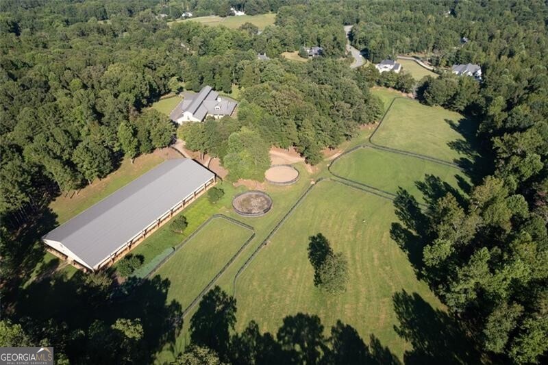 Located on a 38.59+/- acre setting in the heart of Alpharetta horse country, Serenity Farm offers ideal amenities for a private equestrian estate or a professional training operation. Combining the beauty of reclaimed millwork with the strength of concrete construction, the 14-stall custom stable was designed for both premium horse care and entertainment.  The 100x220 lighted, covered arena with slant wall and Futuretrack footing is suitable for many riding disciplines and/or events.  The open and light stable is situated for maximum airflow and drainage and features high T&G ceilings and extra wide aisles with rubber pavers; matted, 14x14 stalls with ventilated front and rear doors;  two large tack rooms plus an owners private tack room all climate-controlled with custom woodwork, built-in tack cabinets and ample saddle/bridle racks; two matted wash racks with stainless cabinets/fans/heaters; separate vet/farrier space; large feed room, equipment/supply room and two blanket rooms.  Overlooking the pastures and riding arena you will find a wrap-around covered porchperfect for entertaining with French doors leading to the full kitchen with lounge and to the office with private bath.  Additionally, there is a large laundry room with built-in cabinetry, two guest baths and two second floor apartments with a kitchen and two baths.  There is also a 2BR/1BA cottage with separate driveway as well as a hay barn, equipment barn and storage shed.  The four-board fenced property features 14 pastures/paddocks, two round pens and wooded riding trails. Bring your builder to create a country compound for generations to come!Located between Canton and Milton, Serenity Farm has easy access to restaurants, shopping and entertainment in Alpharetta, Crabapple, Roswell and Woodstock.