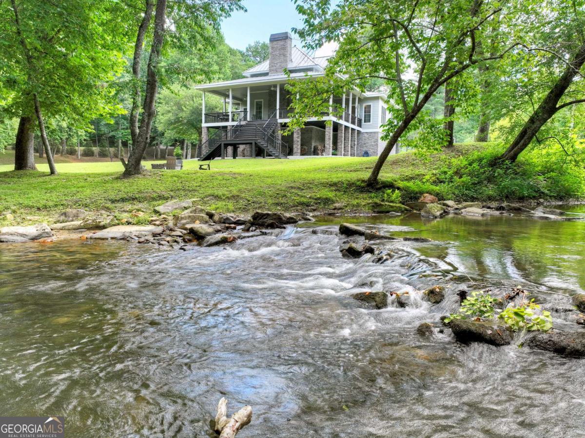 This custom-built home is a rare combination of functionality and luxury, set on over 4.5 usable acres with more than 1,600 feet of frontage on Fightingtown Creek-a premier trout stream. Designed with self-sufficiency and lasting quality in mind, the property includes a large garden, a fruit and nut tree orchard, and a root cellar, offering a true homestead lifestyle in the heart of the Blue Ridge Mountains. The home features over 3,000 square feet of interior living space, with four bedrooms & three full baths. A full unfinished basement with a half bath provides room to expand, and the two-car garage adds practicality and storage. Built with the utmost attention to quality and efficiency, this home includes a standing seam metal roof, geothermal heating and cooling, and low-maintenance, high-durability exterior finishes. Every detail has been carefully chosen for long-term comfort, energy savings, and minimal upkeep. Take in the views and sounds of the creek from almost every room, from the over 1,000 square feet of covered decks, or by the Creekside brick firepit. Enjoy peaceful days fishing from your own private stretch of Fightingtown Creek, harvesting fresh produce from the garden, or simply relaxing in this serene, natural setting. Whether you're looking for a luxurious mountain retreat or a self-reliant mini farm in the mountains, this one-of-a-kind property offers the best of both worlds.