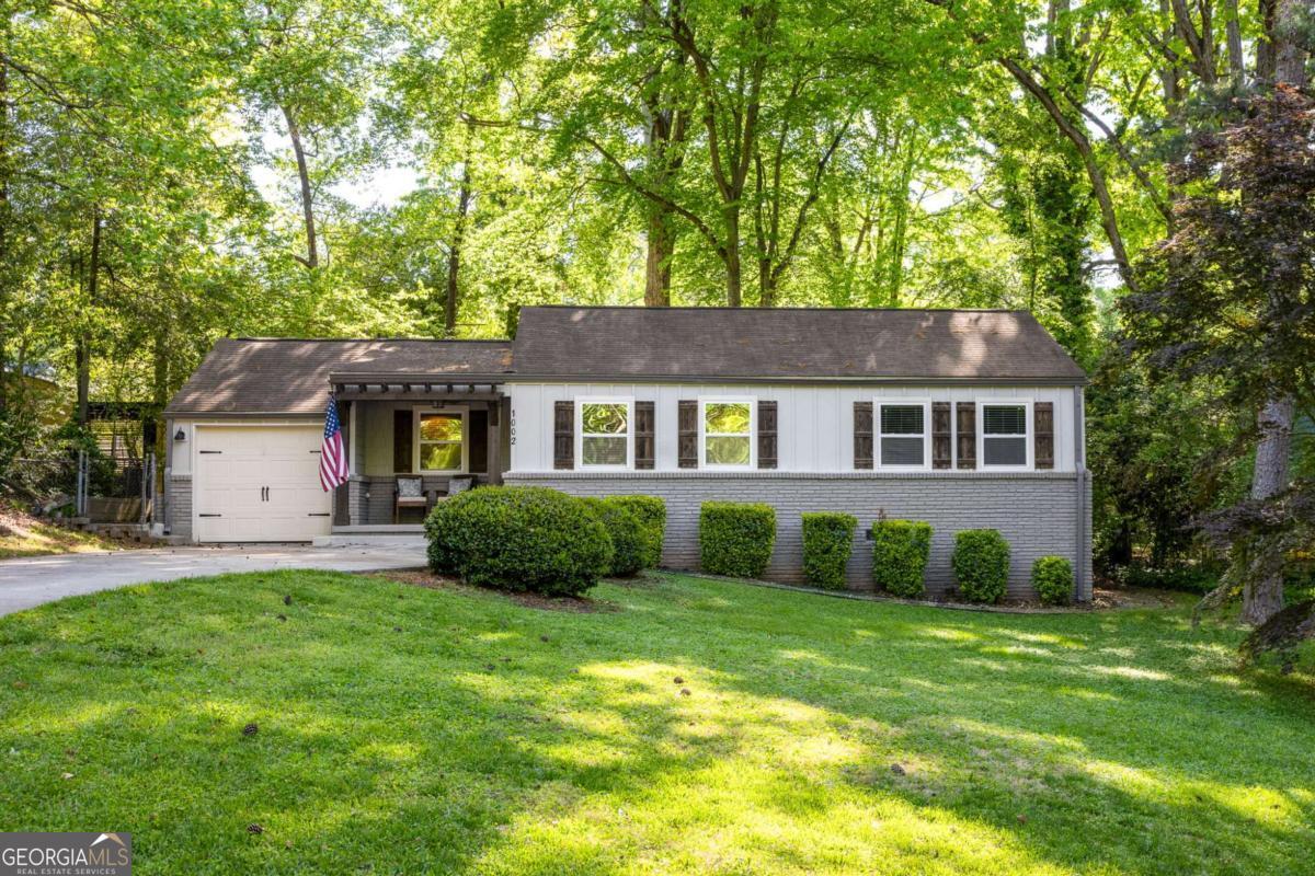 Set back from the street in the heart of Forrest Hills, this beautifully renovated home offers the perfect blend of charm, style, and functionalityCoall with easy one level living. A spacious front porch welcomes you in and is the perfect location for greeting neighbors. Step inside the open floor plan with hardwood flooring throughout. The kitchen is a true showstopper with crisp white cabinetry, custom wood island with waterfall edge, gorgeous tile backsplash, granite countertops, and thoughtful storage throughout. A dedicated dining area provides space to gather and connect. The living room features a classic brick fireplace and stunning vaulted wood ceilings that add warmth and character. The spacious primary suite is a true retreat with a wall of windows overlooking the backyard, a cozy sitting area, a large walk-in closet, and a spa-inspired ensuite bathroom featuring a double vanity and frameless glass shower enclosure. Three additional bedrooms and two more full bathrooms offer flexibility for guests, work-from-home, or growing households. The park-like fenced backyard provides plenty of room to play, garden, or simply relax. Rare single car garage. Incredible location minutes from the Museum School, Legacy Park, Dekalb Farmers Market, Avondale and Decatur shops and restaurants. Enjoy this move-in ready home in a peaceful, connected community.