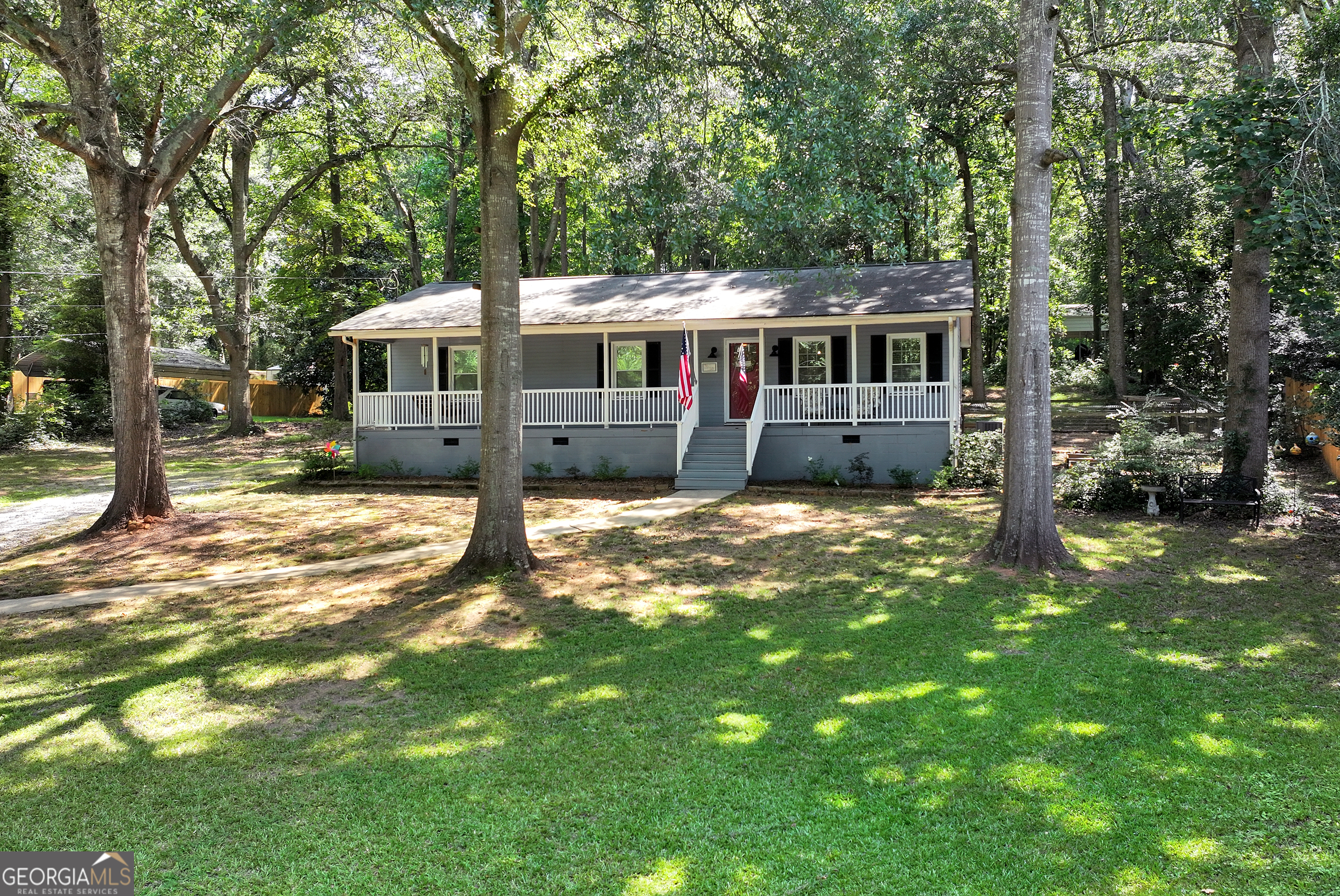 BACK ON THE MARKET- WITH NO FAULT OF THE SELLER OR HOME INSPECTION. Welcome to this charming 3 bedroom, 2 bath ranch farmhouse-style home, nestled in a quite and wooded setting offering privacy and serene surroundings. A welcoming rocking chair front porch sets the tone for this warm inviting home. Inside, the open floor plan features durable LVP flooring throughout and custom barn doors that add a touch of rustic charm. The spacious kitchen boasts granite countertops, large island, stainless steel appliances and pantry. The dedicated dining area, perfectly sized to accommodate all your guest. The Owner's suite offers a tiled walk-in shower, modern finishes and generous space. Two additional bedrooms provide flexibility for guest or a home office. The mudroom features a folding table, extra storage and a doggie door. Step outside to enjoy nature or entertain with ease. This property has direct access to the city park for outdoor fun and picnics. A detached outbuilding offers , storage or workshop space. PRIVATE, PEACEFUL AND MOVE-IN READY.