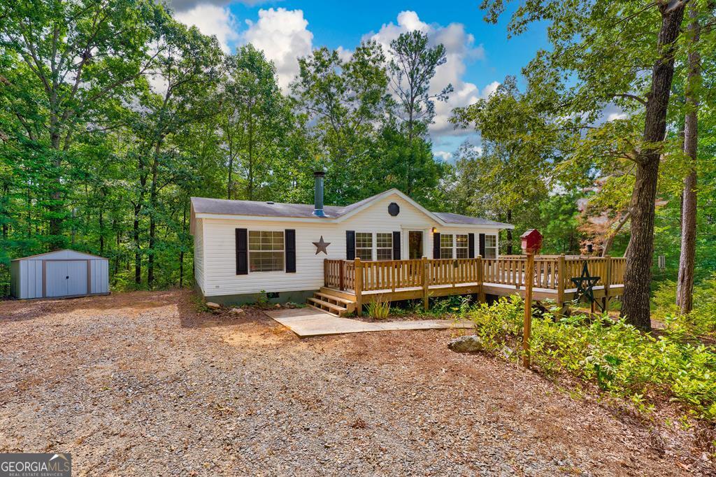 Welcome to this beautifully maintained 3-bedroom, 2-bath residence on a permanent foundation, offering the advantage of easy financing and lasting value. Privately tucked away yet just minutes from downtown Ellijay, this property provides the best of both worlds-peaceful seclusion with convenient access to shopping, dining, and recreation. The inviting interior features a spacious open floor plan, highlighted by a cozy fireplace and abundant natural light. Outdoor living is equally impressive, with a generous deck ideal for entertaining, a charming firepit area perfect for evenings under the stars, and gently rolling, usable land that enhances both beauty and functionality. A small outbuilding adds practical storage, complementing the property's thoughtful design. This move-in ready home is the perfect opportunity for a full-time residence, mountain getaway, or smart investment in the heart of North Georgia.