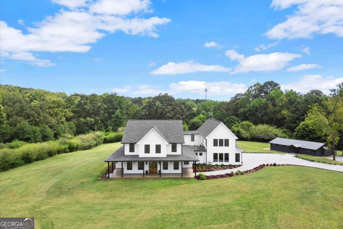 Experience luxury country living just minutes from the city in this stunning new construction home. Offering 7 bedrooms, 5 bathrooms, and 5,007 sq ft of living space on 3.28 serene acres, this property combines modern comfort with a tranquil setting. Designed for entertaining, the home features two full kitchens, an outdoor kitchen with grill station, and a covered patio. Inside, you'll find all stainless-steel appliances, quartzite countertops in both kitchens and the grill station, stone vanities throughout, beautiful flooring, custom wood closet systems, and a spa-like owner's bath with a stone soaking tub. Energy-efficient foam insulation and an electric car charging station complete the modern conveniences. The gated entrance opens to an impressive 300+ foot stone paver driveway, leading to a spacious three-car garage, ample guest parking for 10+ vehicles, and designated RV and boat parking. An additional mid-century converted dairy barn offers endless possibilities as a party barn, guest house, private studio, workout facility, or office/FLEX space. Gather outdoors around 70+ feet of modern fire pits, enjoy low-voltage landscape lighting, and take advantage of the deep well for irrigation. The property is fully fenced with 5-board horse-style fencing and is already approved for a pool, pavilion, and an additional 2,000 sq ft barn or car-collection storage. With its 3,000-gallon septic system, thoughtful upgrades throughout, and unmatched entertaining spaces, this one-of-a-kind retreat delivers the perfect balance of privacy, space, and convenience--luxury country living at its finest.