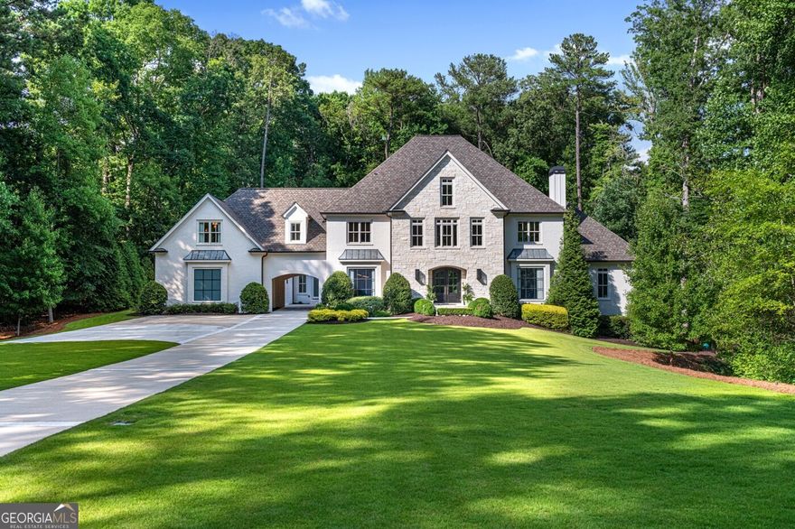 Tucked behind private gates on an expansive 2.1-acre estate in the prestigious Buckhead neighborhood, this exquisite residence is a stunning example of timeless design and refined living. Every element of the home has been thoughtfully curated to blend classical architecture with modern luxury. A dramatic two-story foyer greets you with a sweeping curved staircase and floods of natural light, setting the tone for the sophistication within. To one side, a richly appointed study showcases bespoke floor-to-ceiling millwork and a striking view of the private front landscape. On the other, the formal dining room impresses with detailed trim work, soaring ceilings, and elegant proportions ideal for both intimate gatherings and large-scale entertaining. The main living room offers a harmonious balance of grandeur and comfort, featuring a tray ceiling, a bold stone fireplace, and a wall of windows that seamlessly merge indoor and outdoor living. Adjacent is the chef's kitchen, a true centerpiece of the home, anchored by a stunning marble waterfall island and outfitted with top-tier appliances concealed within custom cabinetry. A burnished brass pot filler, sleek vent hood, and wine refrigerator complete this space designed for both form and function. Flowing naturally from the kitchen, the light-filled family room is a haven for relaxed living, with vaulted ceilings and expansive windows that frame views of the beautifully landscaped walk out turf backyard and open gracefully to an outdoor veranda with automated screens. The main-level primary suite is a serene retreat with a vaulted ceiling and wooded vistas. Its en-suite bath evokes a boutique spa experience, featuring a sculptural stone soaking tub, a dramatic glass-enclosed marble shower, dual vanities with ambient lighting, and his-and-hers dressing rooms finished in rich custom cabinetry. Upstairs, five well-appointed bedrooms each feature private en-suite baths. A separate guest suite includes its own living space and bathroom, offering a versatile area perfect for extended stays, children's activities, or a private lounge. The home also includes an elevator that serves all levels, leading to an impressive terrace level designed for indulgence and leisure. Highlights include a glass-front, climate-controlled wine cellar, a professional-grade home theater, a full fitness suite with a mirrored studio for dance, barre, or yoga, and an additional living area complete with a full kitchen and guest accommodations. Outdoors, this estate continues to elevate the lifestyle with a resort-style saltwater pool and tanning shelf, expansive flat lawn, and dual covered pavilions featuring a wood-burning fireplace and vaulted wood ceilings ideal for alfresco dining and year-round enjoyment. A gated area offers the perfect space for pets or play. This is a rare opportunity to own a truly bespoke residence in one of Atlanta's most sought-after addresses an estate that defines elegance, privacy, and timeless sophistication.