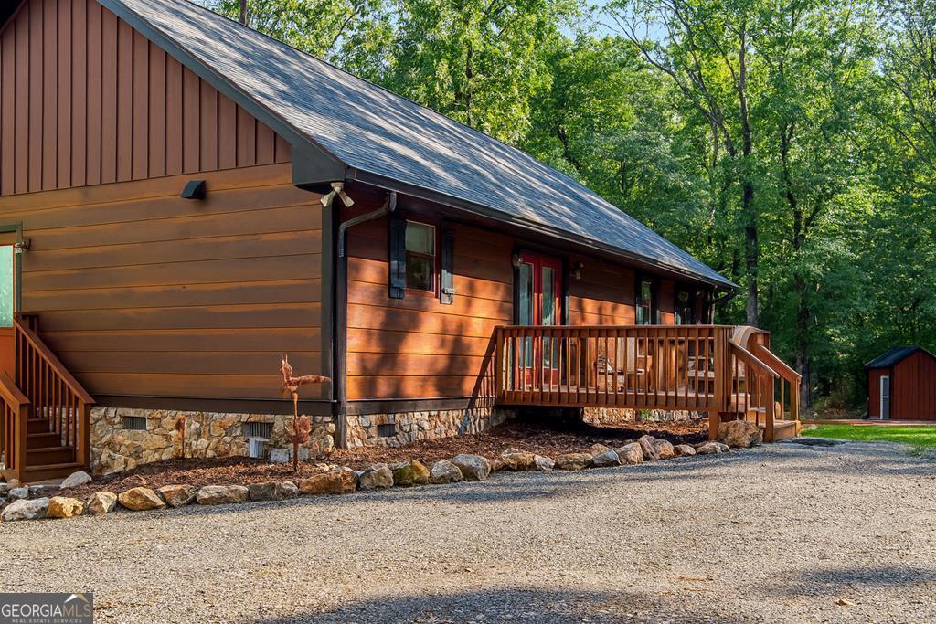 Welcome to 108 Red Hawk Trail - a meticulously maintained, custom-built one owner cabin nestled on 3 private acres in the heart of Ellijay. This charming 2 bed, 2 full bath one-level home offers serene mountain living with modern conveniences. Built just 7 years ago this cabin features a 2018 roof, HVAC, and hot water heater, plus a dual-fuel heating and air system, whole-house water filtration, and an electric monitor for efficient climate control. The kitchen boasts warm wood cabinetry, stainless steel appliances, gas stove, Formica countertops, and durable vinyl planking flooring. Enjoy the open dining area and cozy living room, complete with backup propane heat and space for a future fireplace. Thoughtful upgrades include brand new staining on all porches (front, side, and back), freshly painted trim. 36-inch doorways offering potential wheelchair accessibility. Washer and dryer are conveniently located on the main floor, with a brand-new washer and a separate mudroom entry. The closet near the living area could be easily converted into a bunk room. The spacious master suite includes a massive walk-in closet that could double as an office, and an ensuite bath with vinyl planking flooring, fiberglass surround tub, and linen closet. The guest bedroom and bath offer comfort and convenience with vinyl planking flooring and a fiberglass tub. Outside, you'll find beautiful stonework sourced from the property itself, newly added landscaping, a 330-gallon buried propane tank, and a seasonal mountain view. The 12x16 outbuilding is only 4 years old, ideal for storage, workshop, or hobby space. With a covered picnic area. There's also a firepit area, and ample flat parking. Vacation rentals are allowed, fiber optic internet is available, and the HOA is just $25 a month with a club house and field for playing with a creek! Whether you're seeking a full-time residence, mountain getaway, or short-term rental opportunity-this property checks every box! Conveniently close to hiking trails, fishing,and biking areas, many Apple Orchards and Wineries!