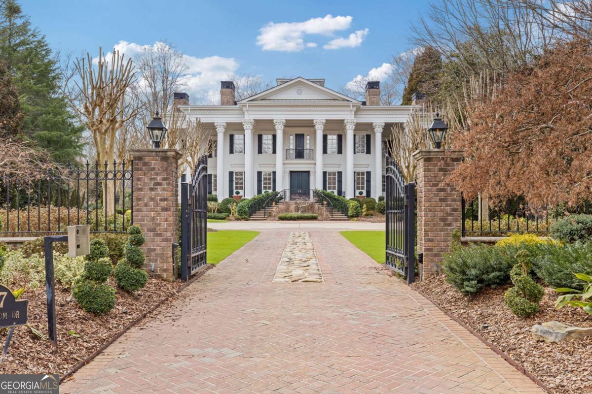 Nestled along the serene Chattahoochee River in Duluth, Georgia, 3977 Sweet Bottom Drive is a distinguished Greek Revival estate that epitomizes luxury living. Built by a well known builder for his personal residence in 2003, this spacious residence encompasses nearly 14,000 square feet and features 6 bedrooms and 8.5 bathrooms. Set on over an acre of property with 129' of shoreline, this home boasts an expansive front porch with 26' high Corinthian columns, 13 fireplaces, a grand two-story foyer, leading to formal living and dining rooms adorned with intricate moldings and hardwood floors. The gourmet kitchen is equipped with high-end appliances, custom cabinetry, and marble countertops, seamlessly connecting to a cozy fireside keeping room and a spacious family room. A sun-drenched sunroom with charming brick flooring and a tongue-and-groove ceiling offers a tranquil retreat and overlooks the incredible backyard. An impressive custom paneled office completes the first floor. Upstairs, the luxurious owner's suite features a spa-like bathroom with dual vanities, a soaking tub, and a separate shower as well as another private space for an office or zen room and multiple walk-in closets. Additional bedrooms are generously sized, each with en-suite bathrooms. The finished basement includes a home theater, wine cellar, work out room, rec space, an indoor spa and ample storage space. There is an elevator that services all four floors of the main residence. A separate "nanny or in-law" suite features an additional living space, laundry room, kitchen, bedroom and full bath. Set on a meticulously landscaped lot, the property includes a motor court in the front, a four car garage, and a private backyard with a pool, spa, and outdoor kitchen, outdoor fireplace - ideal for entertaining. The estate is situated within the exclusive, gated Sweet Bottom Plantation community, featuring amenities such as a clubhouse, tennis courts, community pool and walking trails. This exceptional home combines timeless elegance with modern conveniences, providing a luxurious lifestyle in a picturesque setting with a very convenient location.