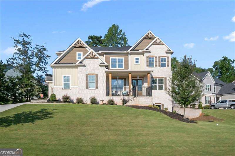 **Better Than New!** Discover this stunning two-year-old home with custom upgrades in the highly sought-after Traditions of Braselton community. This spacious residence offers five bedrooms and four full bathrooms, providing ample room for a large family, home office, or guests. As you enter through the elegant double front doors, you'll be greeted by a beautifully designed space. The expansive, separate dining room features a connected Butler's Pantry, perfect for effortless entertaining. Adjacent to this is a charming glass-enclosed area, ideal for a quiet reading den, a convenient workout space, or a stylish home office. The great room is truly breathtaking, boasting a soaring 24-foot wood-beamed ceiling. Natural light floods the room through windows on both the main level and high above. A stone fireplace with a paneled wall and built-ins adds warmth and comfort to the space. The kitchen is a chef's dream, open and bright with quartz countertops, a beautiful textured tile backsplash, and Viking stainless steel appliances. A pot filler over the stove enhances cooking convenience. The oversized island offers plenty of seating, and the keeping room can serve as an additional breakfast area. The main level also includes a guest bedroom and a beautifully appointed full bath. Step outside to the covered living area, which leads to a firepit and offers stunning golf course views, expanding your entertainment options. The unique oversized primary suite features a wood-planked tray ceiling, an upscale fan, a sitting area, and an ensuite bathroom with double vanities, a soaking tub, and a spacious shower with a rain showerhead. The walk-in closet, complete with a center island, provides ample storage for all your clothing needs. Iron balusters lead up to the loft, which overlooks the great room. Each bedroom is generously sized and has access to private bathrooms, with elegant accent walls adding a touch of sophistication. A three-car garage (two-car plus an additional one-car) and a spacious driveway offer abundant parking for family and guests. The full unfinished basement, with high ceilings and plumbing for a bath, offers endless possibilities. With a private entrance, it can be transformed into extra living space or a complete second apartment. Enjoy the convenience of a golf cart to explore the community's amenities, including swimming, tennis, pickleball, a playground, and a clubhouse. The vibrant social activities make this a highly desirable community. Located close to schools, Gun Springs Park, wineries, healthcare facilities, restaurants, shops, and Historic Downtown Braselton, this home offers everything you could want or need.