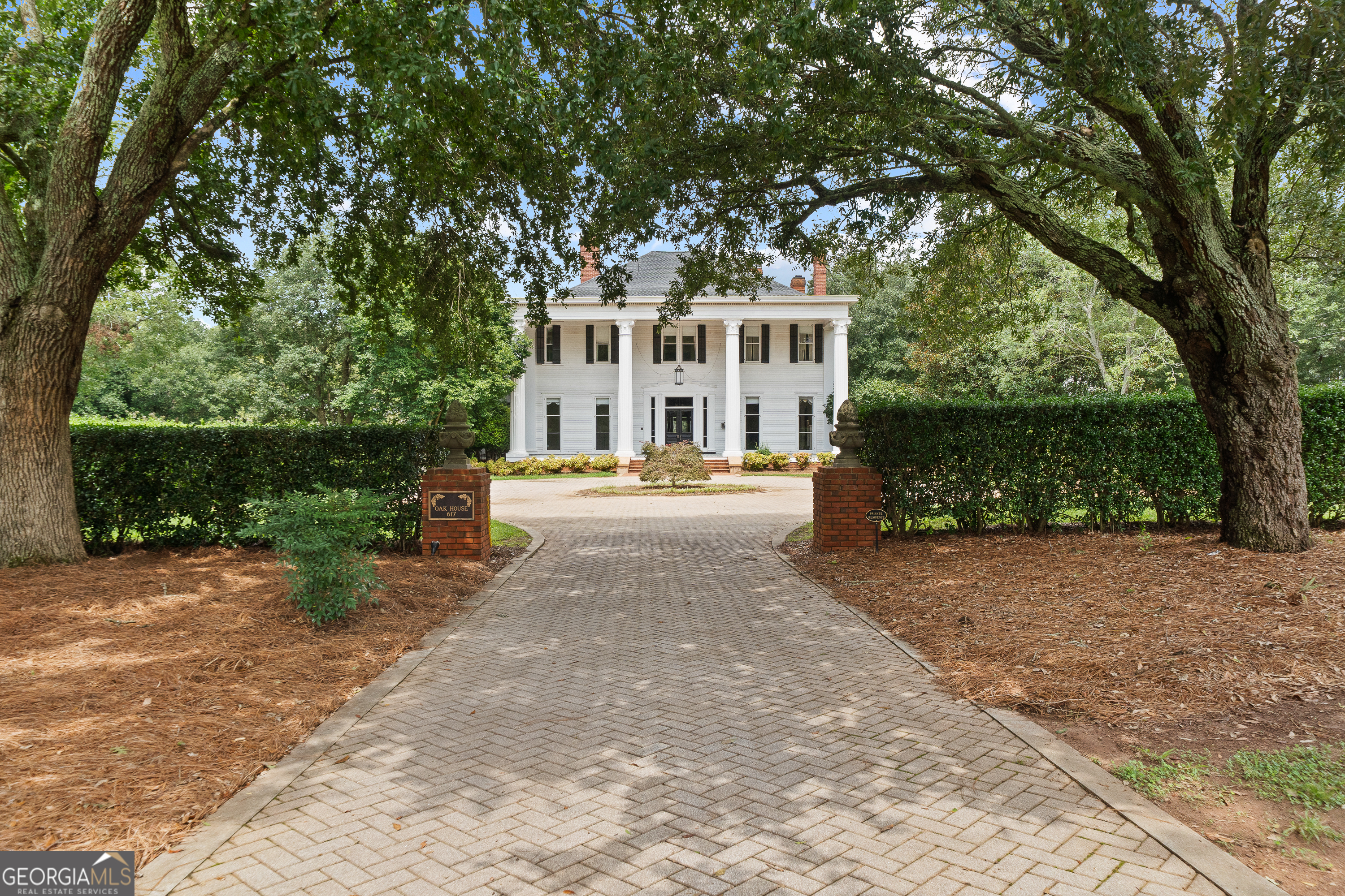 Historic Grandeur Meets Modern Luxury in the Heart of Madison, The Oak House, Circa 1897 A rare offering in Madison's Historic District, The Oak House stands as a crown jewel of Southern architecture. Originally built in 1897 and honored with a Georgia Trust Award for Historic Preservation, this New South Neoclassical Revival estate sits prominently at the corner of Walton Street and Dixie Avenue, surrounded by formal boxwood gardens, mature trees, and a gated circular drive. Painstakingly restored and expanded with period-sensitive additions beginning in 1992, the home seamlessly blends historic detail with luxurious modern living. Grand yet welcoming, the interior showcases curved doorways, intricate fireplace mantels, and a soaring three-story foyer with a dramatic oak-carved staircase beneath stained-glass skylights. Entertain with ease in the formal double parlors, wet bar, and banquet-sized dining room that seats over 20. The richly appointed smoking room features a coffered ceiling, wood paneling, and built-in bookcases, while the sunroom, den, and spacious side porch offer a range of relaxing retreats. The chef's kitchen boasts an eat-in area, butler's pantry, and direct access to multiple dining and gathering spaces, including covered back decks on both levels. An elevator provides easy access to all floors. The luxurious primary suite is its own private retreat, complete with his-and-hers custom walk-in closets, dual bathrooms, a private exercise room, and access to the upper-level porch. Additional features include: Home office, basement level with wine cellar, gym, two half baths, walk-in cooler, laundry facilities, utility room, and two garage bays, a 1950 square feet guest house with 2 bedrooms, 2 full baths, and 1 half bath, private pool surrounded by lush landscaping, 3-car detached garage, greenhouse for gardeners and hobbyists and a unique train room in the finished attic-ideal for collectors or creatives. This one-of-a-kind estate offers the perfect fusion of historic charm and modern luxury, all just steps from Madison's beloved downtown. A timeless Southern masterpiece, The Oak House is a home of unparalleled character, elegance, and legacy.