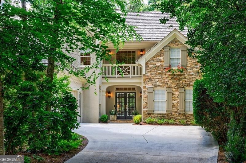 COUNTRY CLUB OF THE SOUTH quintessential Manor home is set on a private lot in one of Atlanta's most coveted gated communities, this classic hard-coat stucco and stone residence offers timeless charm and elegant curb appeal. A long, stately driveway leads to this beautifully designed home featuring a cedar shake roof and a charming Juliet balcony setting the tone for the warm welcome inside. Step through double front doors into a soaring two-story foyer that introduces the home's gracious layout. The formal dining room is banquet-sized, ideal for both hosting large gatherings and enjoying intimate dinners. The two-story great room is filled with natural light, showcasing a fireplace flanked by built-in bookcases and a wall of windows that invite the outdoors in. The heart of the home is the chef's kitchen, featuring exquisite Taj Mahal quartzite countertops, Wolf appliances, Sub-Zero refrigerator, a walk-in pantry, and custom inset cabinetry with soft-close hardware. Adjacent to the kitchen, a cozy keeping room is surrounded by windows, while a spacious custom sunroom offers an additional main-level living area with tranquil views. The main-level primary suite is a true retreat, with direct access to the expansive deck and a luxurious marble-clad bathroom featuring marble floors, countertops, and backsplash. Two walk-in closets have been thoughtfully customized by California Closets. Upstairs, you'll find three generously sized bedrooms one with an en-suite bath and two that share an adjoining bathroom all with large closets and plenty of natural light. The walkout terrace level is designed for both relaxation and productivity, including a large family room perfect for movie nights, a custom California Closets workspace with multiple built-in desks, and a flexible room ideal as a guest suite, gym, or activity space. There is also an unfinished area perfect for a workshop or future customization. Enjoy serene outdoor living on the main-level deck, complete with an electronic retractable awning for effortless shade. Experience resort-style living in the gated and amenity-rich Country Club of the South, nestled in the number one ranked US city of Johns Creek, Georgia.