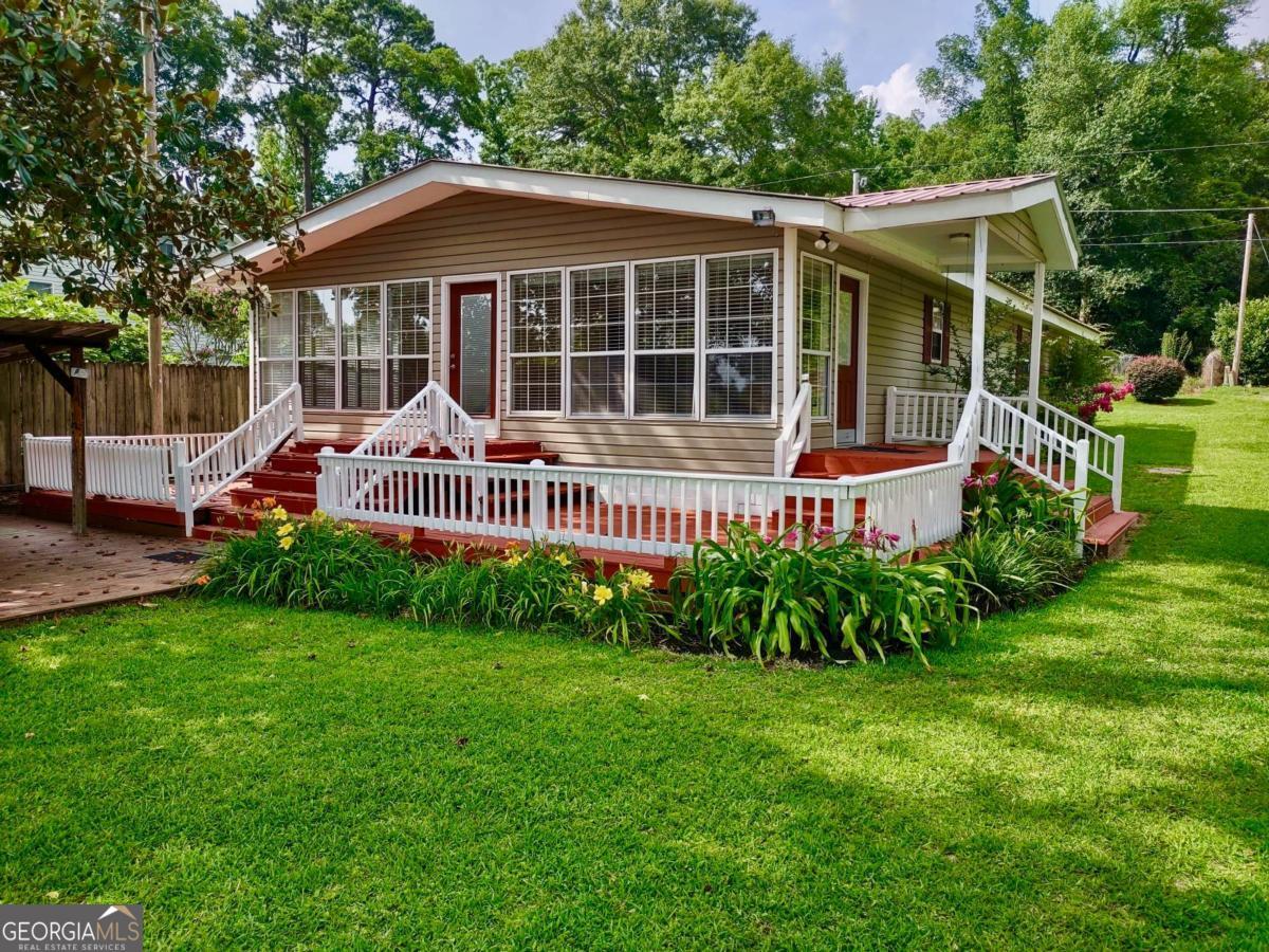 This charming 3-bedroom, 2-bath home on the south end of Lake Blackshear offers the perfect blend of lakeside living and convenience. Located near Smoak Bridge, Striplings General Store, Blackshear Beverage, and Salt Lick Sausage Company, it's just minutes from local favorites. With excellent fishing and deep-water access, the property features a covered dock with two slips, making it ideal for boating and outdoor activities. The open-concept kitchen and living area create a spacious and welcoming atmosphere, while the separate den, featuring vaulted ceilings and a gas fireplace, provides a cozy retreat. The master suite includes a large walk-in closet and an ensuite bath with a garden tub and a tiled walk-in shower. Outside, you'll find a large wood deck, a covered entertainment patio, and three storage sheds, offering plenty of room for outdoor living and storage. This property perfectly combines comfort, convenience, and a prime lakeside location, making it an ideal choice