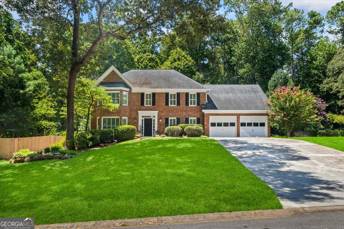 Welcome to your dream home in the prime location of East Cobb & Roswell-where timeless charm, modern updates & exceptional living spaces come together. From the moment you arrive, the home's elevated curb appeal and classic Colonial brick-front facade make a stunning first impression. With all-new energy-efficient windows throughout, this residence blends style & practicality perfectly. Step inside to a grand two-story foyer &warm hardwood floors that flow seamlessly across the main level. Just off the entry, glass French doors open into a versatile front room-ideal for a home office or formal living space-complete with a large bay window overlooking the manicured front yard. The heart of the home lies in the inviting fireside family room, where built-in bookshelves surround a gas log-burning fireplace & wet bar adds a touch of function and flair. This space flows beautifully into a generously sized sunroom, perfect for relaxing while enjoying views of the private backyard in year-round comfort. From the sunroom, enjoy effortless access to a screened-in patio with dual ceiling fans, creating an ideal indoor-outdoor living experience. Easy walk-out (no stairs) to patio, grass backyard, natural areas with mature landscaping PLUS upper yard contains a firepit, this home is IDEAL for entertaining, kids/pets playing & everyday enjoyment. The sun-filled kitchen is a dream for any cook or host, showcasing a wall of windows, neutral gray cabinetry, solid surface countertops, stainless steel appliances including a double wall oven, separate cooktop, built-in microwave, large center island & peninsula overlooking a charming breakfast nook with yet another bay window. With an abundance of prep &serving space, a dedicated coffee station, and a separate walk-in pantry, the kitchen offers both function & beauty. A formal dining room ready to host special occasions.. Adjacent to the garage entry, a mudroom keeps daily life organized with space for backpacks, sports gear &more. Upstairs, the luxurious primary suite offers a peaceful retreat with rich hardwood floors, tray ceiling & a sitting area by a quaint bay window. Two walk-in closets feature barn-style sliding doors and custom built-ins, while the spa-inspired ensuite bath steals the show with a freestanding soaking tub beneath a picture window, a large glass shower with bench under a skylight, spacious double vanity & private water closet with a window. Four additional secondary bedrooms upstairs offer brand-new carpet & ample closet space, with two bedrooms offering walk-in closets. A beautifully renovated shared bath features new lighting, vanity & flooring. An oversized fifth bedroom-with back staircase access-offers flexible use as a guest suite, teen hangout, or upstairs media room. Additional upper-level perks include a large walk-in hall storage closet (potential for a third bathroom- if desired) & large laundry room featuring a folding station & extra cabinetry. Notable features include smooth ceilings throughout, detailed crown molding, plantation shutters, neutral interior paint, a detached storage outbuilding & fully fenced backyard. NEW double pane Low-E windows (designed to significantly improve a home's energy efficiency & comfort.) Nicely nestled at the very back of East Spring Lake-offering ultimate privacy with no through traffic-this home is part of a welcoming East Cobb community filled with charm & character. The neighborhood boasts resort-style amenities, including an large pool with waterfall and swim team, scenic lake view clubhouse with rocking chair wraparound porch, tennis courts with pickleball, sidewalks, and playgrounds. Enjoy a truly unbeatable location, just minutes to schools, parks, shopping & only about 10 minutes to historic downtown Roswell & Chattahoochee River at Azalea Park. Move-in ready gem is one you don't want to miss!