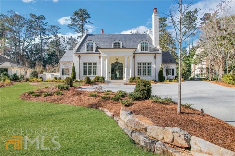 There was no detail overlooked in this stunning new construction in the coveted Tuxedo Park. Completed in 2021, this 8 bed, 7 full bath and 3 half bath home was the product of a collaboration between the Architects at Harrison Design and Builder Rick Fierer with Bildon Construction. The design gives the essence of old Atlanta with a traditional look and contemporary features, perfectly balancing elegance with an inviting and intimate feel. A double gated 24" custom masonry security fence guides you to the property tucked back on a beautiful flat lot. Custom steel doors lead you to the interior where you'll find soaring ceilings, gorgeous Venetian plaster, and 8" white oak floors all flooded with natural light. An open concept layout on the main level seamlessly connects the main living area, kitchen and sitting room which all feature floor to ceiling window walls overlooking the stunning outdoor living space and heated saltwater pool. The main floor living areas are adorned with an Isokern masonry fireplaces with Francois custom limestone mantels and hearths and hand hewed custom whitewashed beams that add to the inviting nature of the home. The gourmet kitchen is perfection, lined with leathered Calcutta Gold on the large island and full height backsplash, Block and Chisel cabinetry, full Sub-Zero appliance package and an accompanying catering kitchen and butler's pantry. The main level primary bedroom features striking vaulted ceilings, private access to the outdoor living area and pool, and ensuite primary bath with honed and polished mystery white marble counters, shower cladding, handmade ceramic tile, heated floors and a steam shower. Entertaining is a must with the lower level featuring a fully equipped bar, state of the art theatre projection and a temperature-controlled wine room with a 1200 bottle capacity. A detached guest house just steps from the main residence would be the perfect in-law suite or private office. Additional enviable features include gourmet outdoor kitchen and built-in grill area, elevator access to all three floors and fully automated smart house Lutron and four control integration.