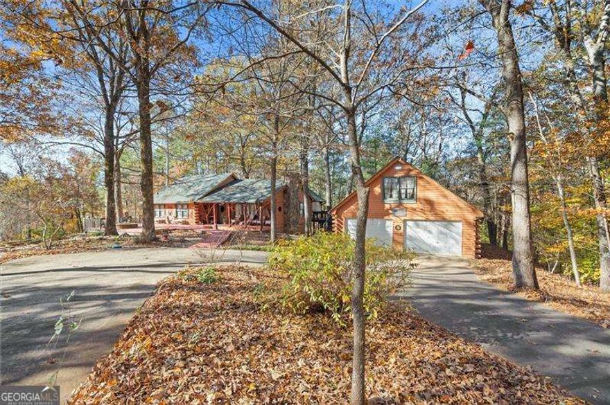 Charming Log Home on 10.8 Private Acres - Perfect for Homesteading & Country Living. Discover the beauty and serenity in this inviting log home surrounded by nature. This property offers the perfect setting for a peaceful retreat, self-sufficient lifestyle, or homesteading dream. You will immediately be greeted by a covered rocking chair front porch and a huge deck with a built in fire pit. Couldn't ask for a better spot for morning coffee or afternoon cocktails.  Step inside to find a warm, rustic interior with wood finishes throughout, an open floor plan, and a beautiful stone, wood burning fireplace prefect for the upcoming cold nights. The home offers cozy living spaces and scenic views from every window, creating an atmosphere of comfort and tranquility. The kitchen features stainless steel appliances and is open to the breakfast room and large living room with vaulted ceilings. Main level has 3 bedrooms, 2 bathrooms. Full Basement has a huge open concept family room with a cozy woodburning stove. Convenient full bathroom in the basement with 2 extra rooms currently being used as a craft room and a canning/food storage room.  Outside, the land is ideal for organic gardening, composting, and small-scale farming with chickens, raised beds and composting site already in place.  A detached two-car garage provides ample parking and includes a full upper-level storage area, perfect for a studio or additional storage space. And you don't have to drive to the mountains to get this! While this peaceful log home feels worlds away, it's perfectly situated just minutes from modern conveniences and local attractions. Enjoy easy access to shops, restaurants, and even a local winery. Spend weekends exploring the nearby Lake Allatoona, where you can swim, boat, or fish, or head to the beach area of Sweetwater Creek Campgrounds for picnics, lakeside relaxation, and fun summertime activities. Enjoy the privacy and quiet of your own slice of paradise, with space to explore, grow, and relax. Whether you're seeking a sustainable lifestyle or a peaceful getaway, this property offers endless possibilities.